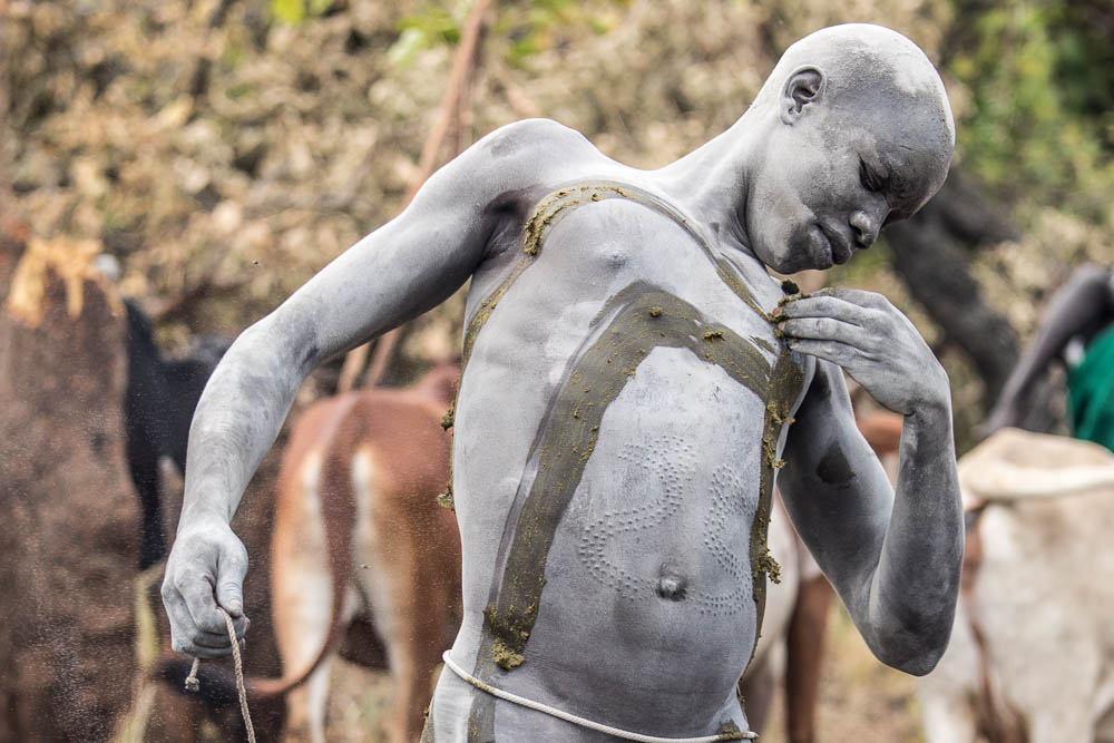 The Suri may also mark their bodies with clay or in this case fresh cow manure. Note the body scars.
