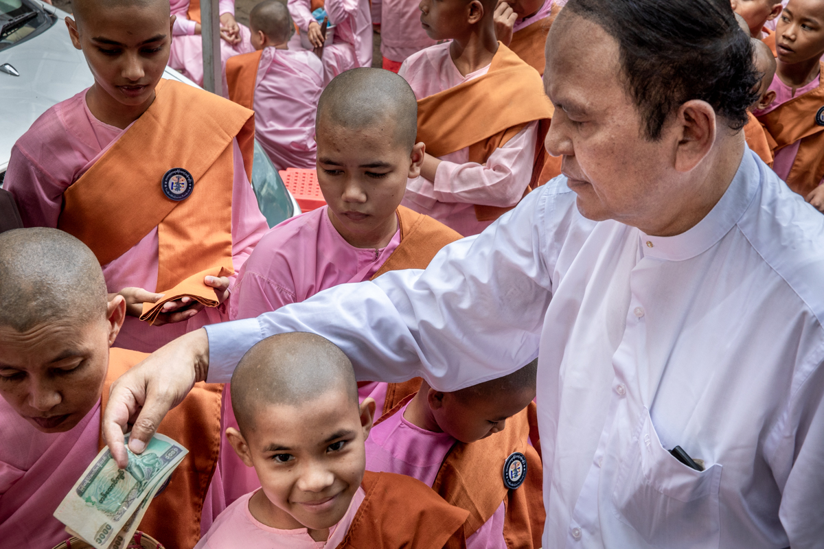 U Aung Than Sein distributing donations to the nuns. He is now assisted by his extended family so that the large number of small bills can be efficiently distributed.