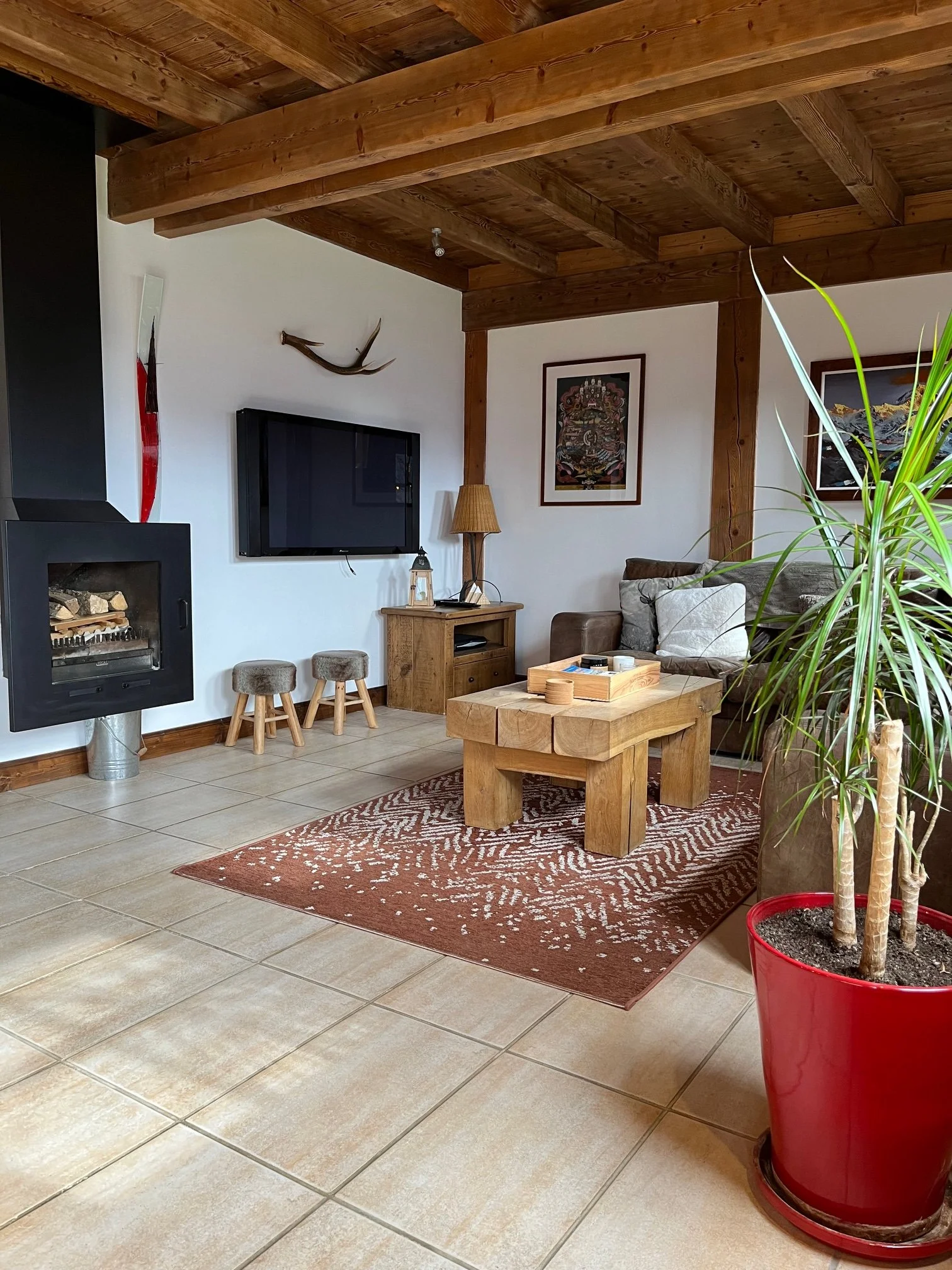 Living room at Chalet Le Pery with leather sofas, wooden beams and wood-burning stove