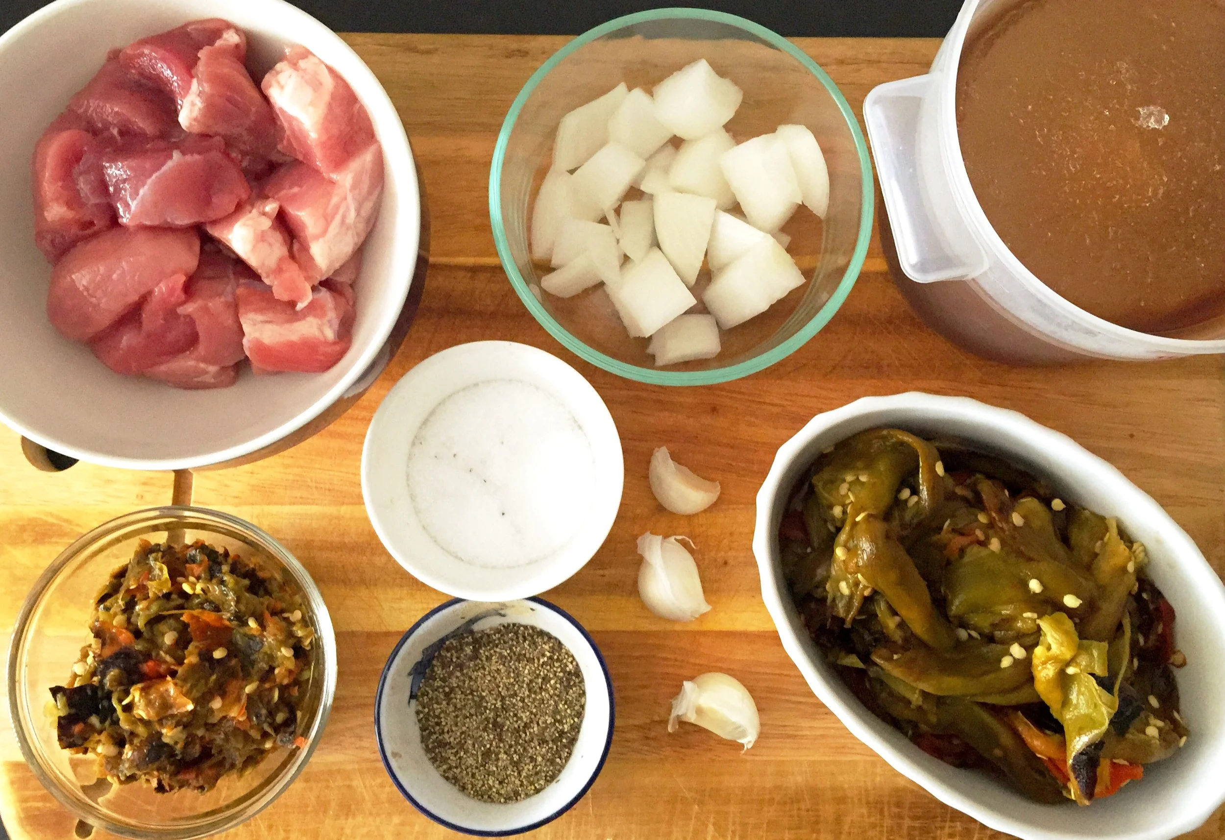Ingredients for the Pork in Salsa Verde Ingredients 1 c pork shoulder (cubed) 1/2 onion (diced) 1/2 c pureed hatch chiles 1 1/2c roasted chiles 3 garlic cloves (peeled and whole) 3 c vegetable stock 2 tbs oil Salt and Pepper to taste Preparation 1. Peel skins of the chiles and discard. 2. Puree the chiles and set aside. 3. Heat a stock pot on high, then add oil. 4. Add your cubed pork and sear about 3 minutes on each side. 5. Remove from pan onto a plate to rest and add your onions and cook for 7 mins. 6. Add the puree chiles, stock, garlic (pinch of salt and pepper) and stir to combine and to loosen up the burnt bits on bottom of pan (where flavor town lives). 7. Add back your pork and bring entire pot to a boil. 8. Put lid on and lower heat to a simmer and cook for 2 hours. Serve dish with a dollop of sour cream and minced cilantro. Enjoy with Rice and Beans.