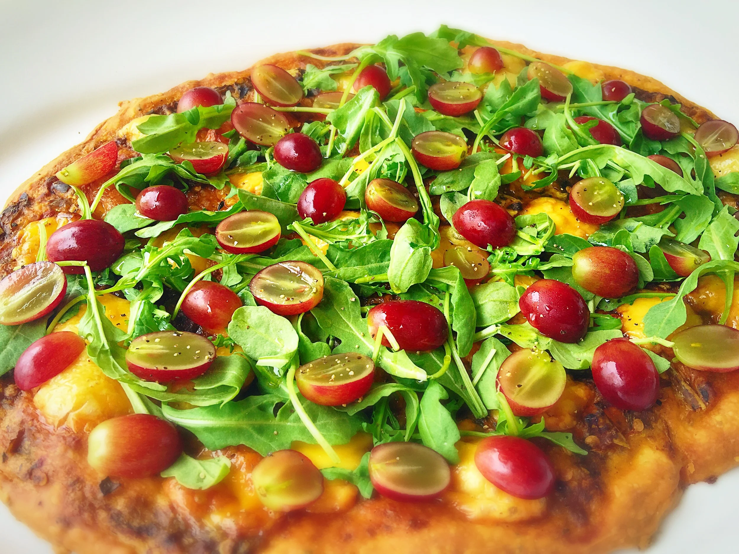 Hatch Chile Flatbread with Arugula and Grapes Ingredients Store bought Pizza dough (to save time) 1/2 c pureed chiles (use the whole roasted chiles from last recipe) 3 tbs water 1 c shredded cheese (I used white cheddar) 1 c sliced grapes 1 c arugula leaves Preparation 1. Mix the pureed chile with the water to make a spreadable base sauce. Top with the cheese and bake according to the directions. 2. Add the Arugula leaves and the grapes and slice immediately.