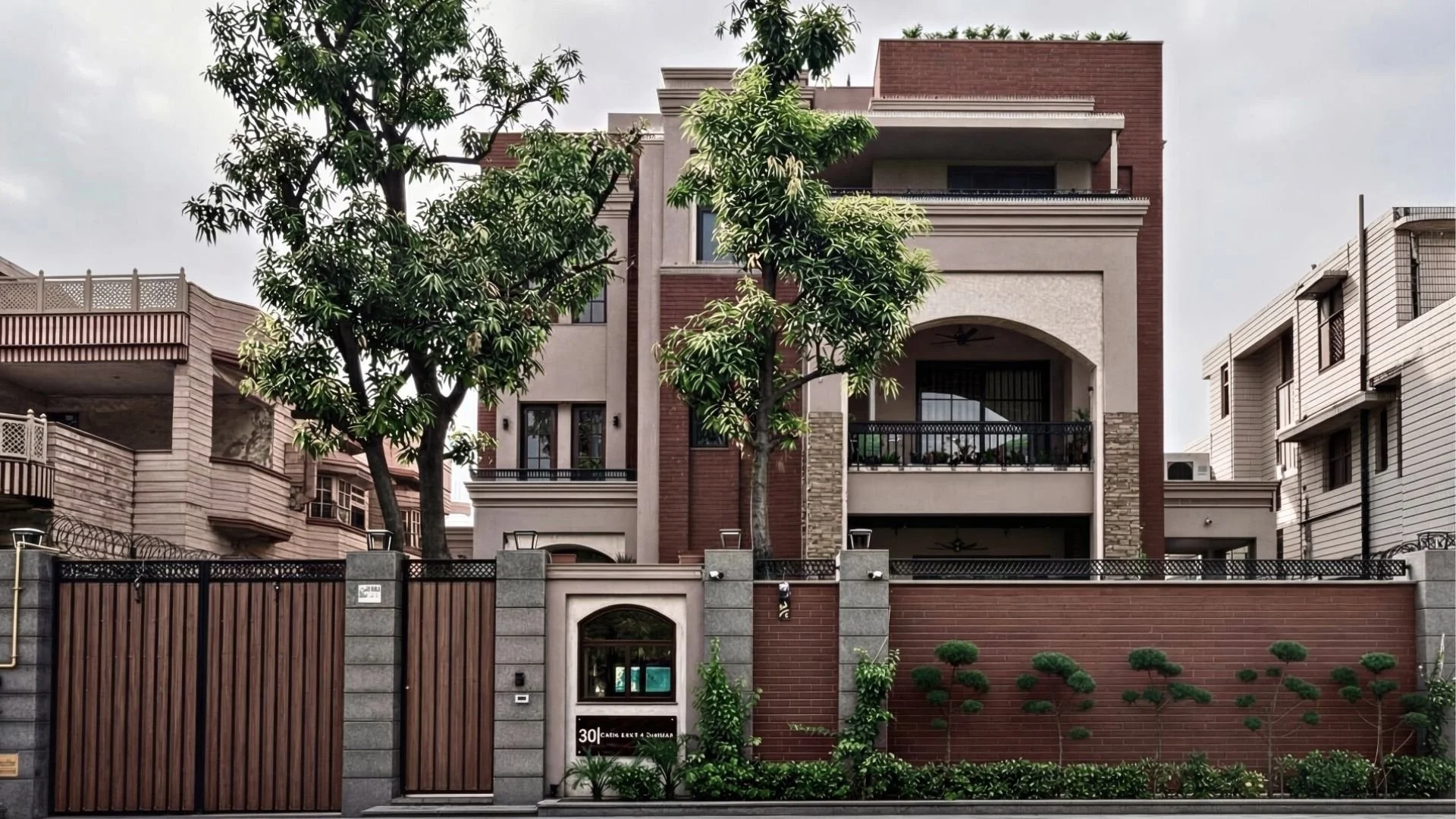 Multi-story residential building with balconies, trees in front, brick and stucco exterior, and a gated entrance with a small garden.