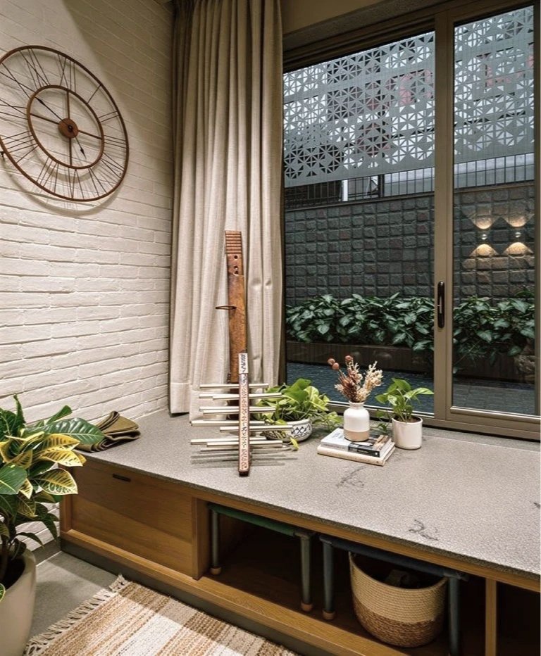 Interior room near a sliding glass door with potted plants, decorative items, and a wall clock.