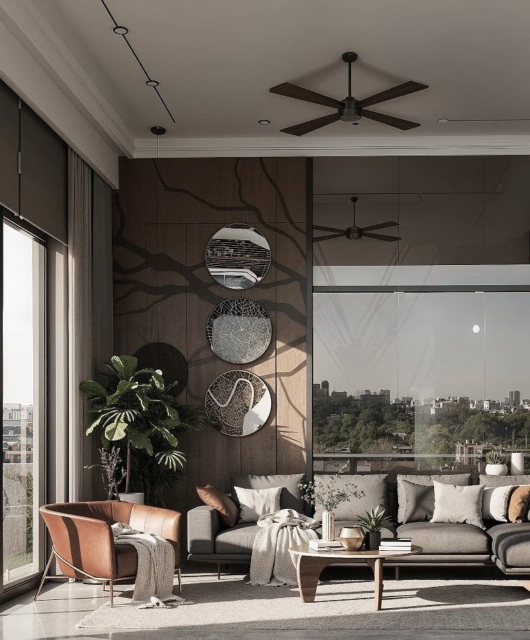 A modern living room with a gray sectional sofa, throw pillows, and a throw blanket. A brown armchair with a throw blanket is near a large window. Decor includes a large plant, circular wall mirrors, and a wooden coffee table with books and decorativ