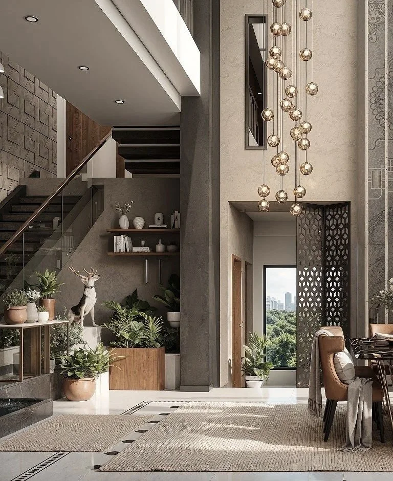 Modern living space with high ceilings, large window showing city view with trees, decorative hanging pendant lights, staircase with glass railing, and indoor plants. There is a deer statue among the potted plants near the staircase.