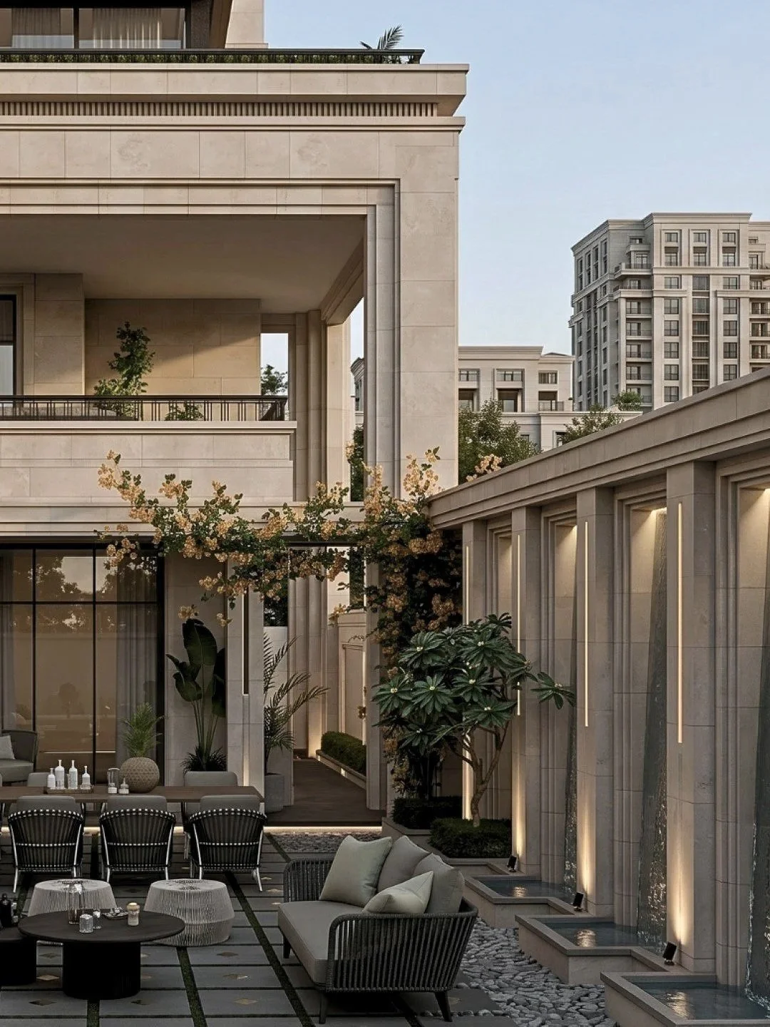 Luxury outdoor patio with modern furniture, plants, and water features in a high-end residential complex.