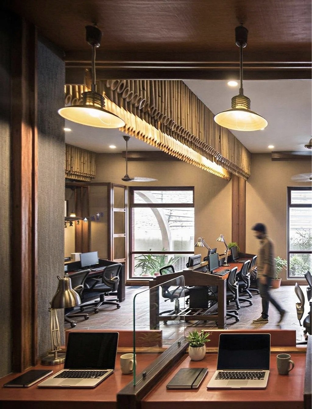 Modern office space with wooden accents, multiple computers, and a person walking past.