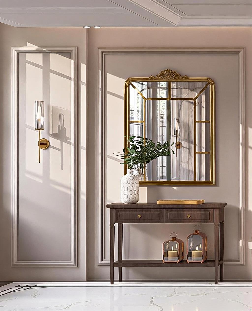 A stylish interior hallway features a dark wooden console table with a white hexagon-patterned vase holding green foliage, a gold framed mirror, and two lantern-style candle holders on the lower shelf. The wall is adorned with elegant white molding a