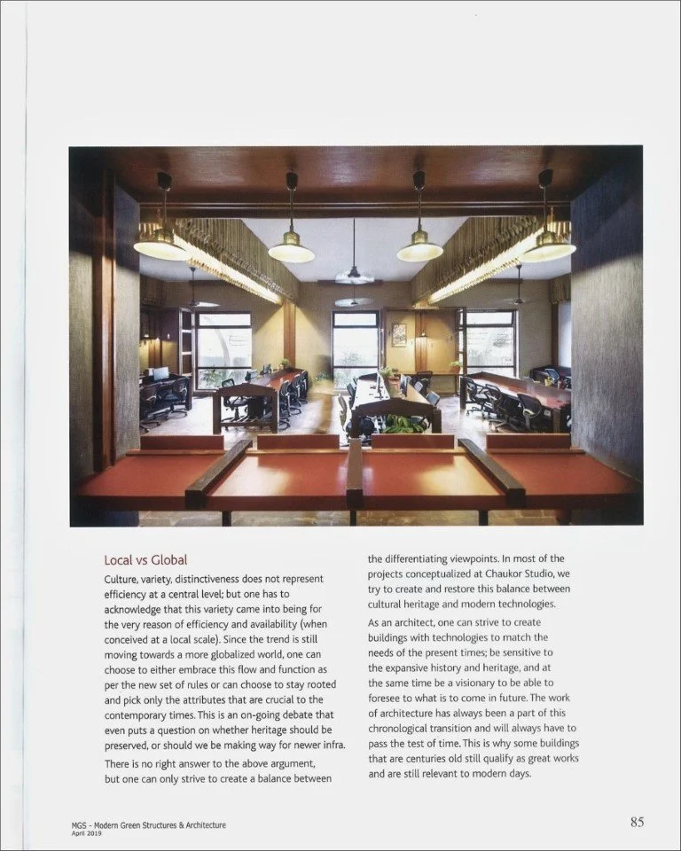 Photo of a modern office space with desks, chairs, windows, and pendant lighting.