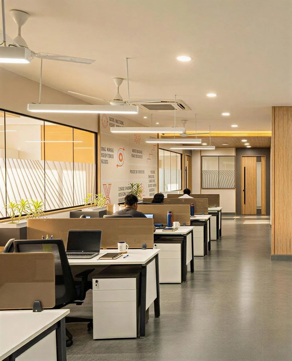 Modern office workspace with desks, computers, and employees working, featuring warm lighting, wooden accents, and wall decor.