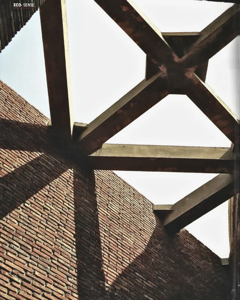 A view looking up at a brick wall and the shadows cast by a wooden fire escape staircase against the wall.