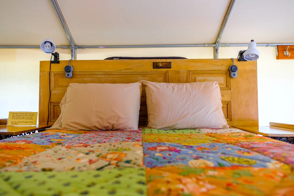 Each tent has a unique custom headboard, lights, power and fan to keep you cool on hot nights. Don't forget the comfy bed. 