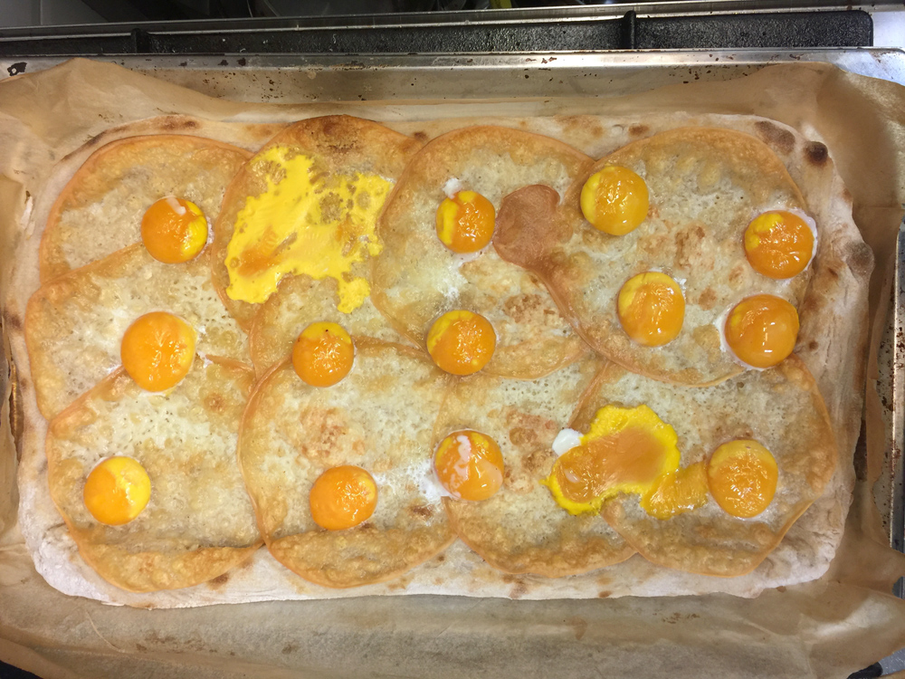 pizza with egg yolks ready to be topped with black truffle shavings