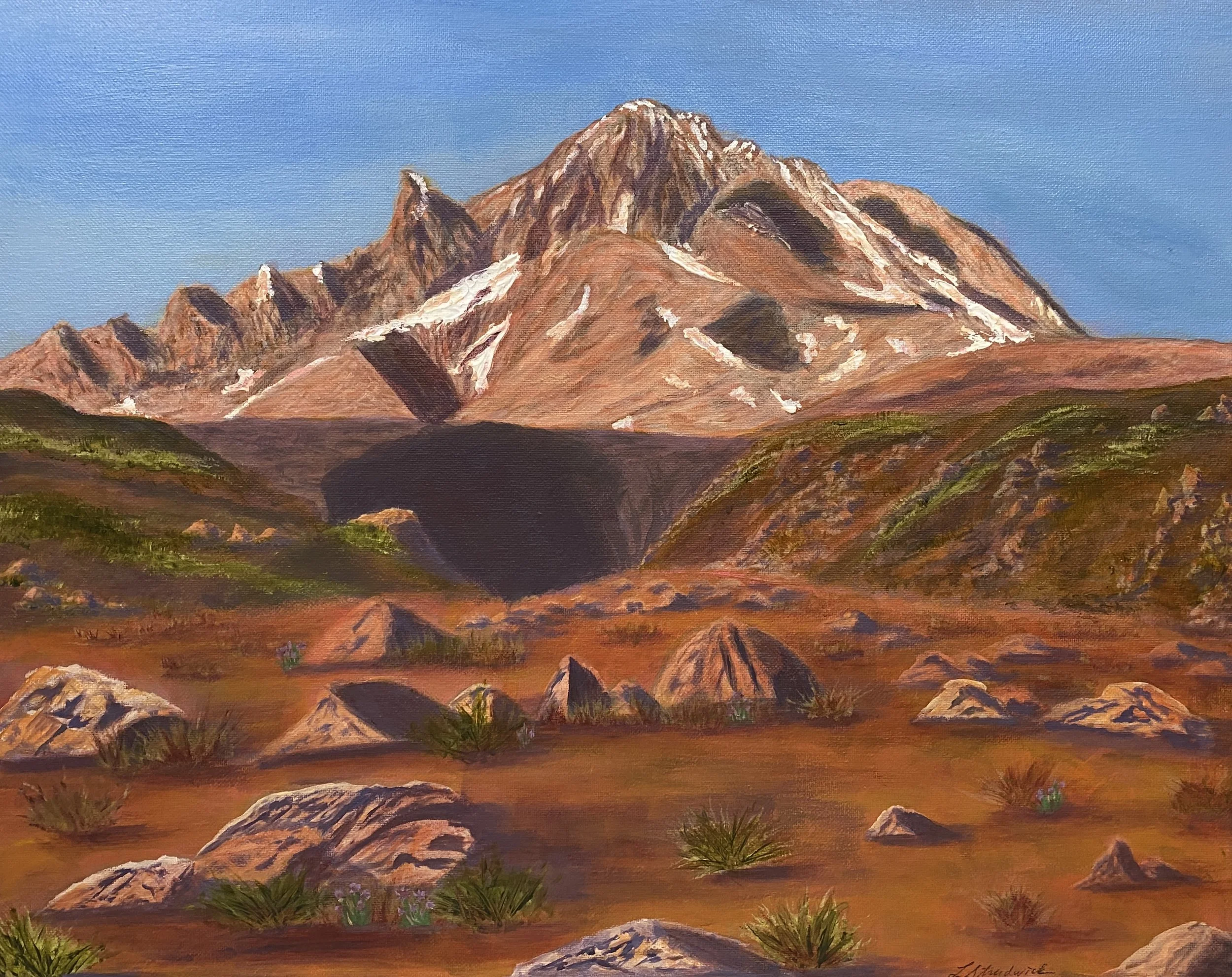 Mountain summit at sunset with alpenglow and rocks in foreground