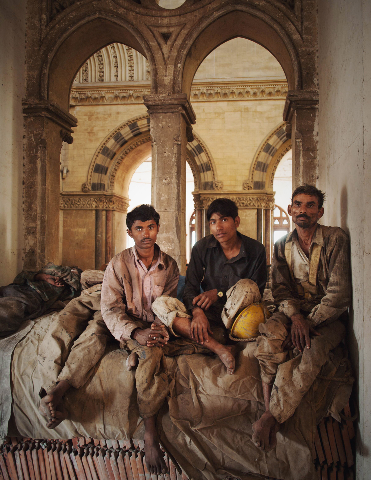 Workers at rest in the gothic columns of CST train station, Mumbai. The men had just finished a shift replacing tiles on the roof of the building.