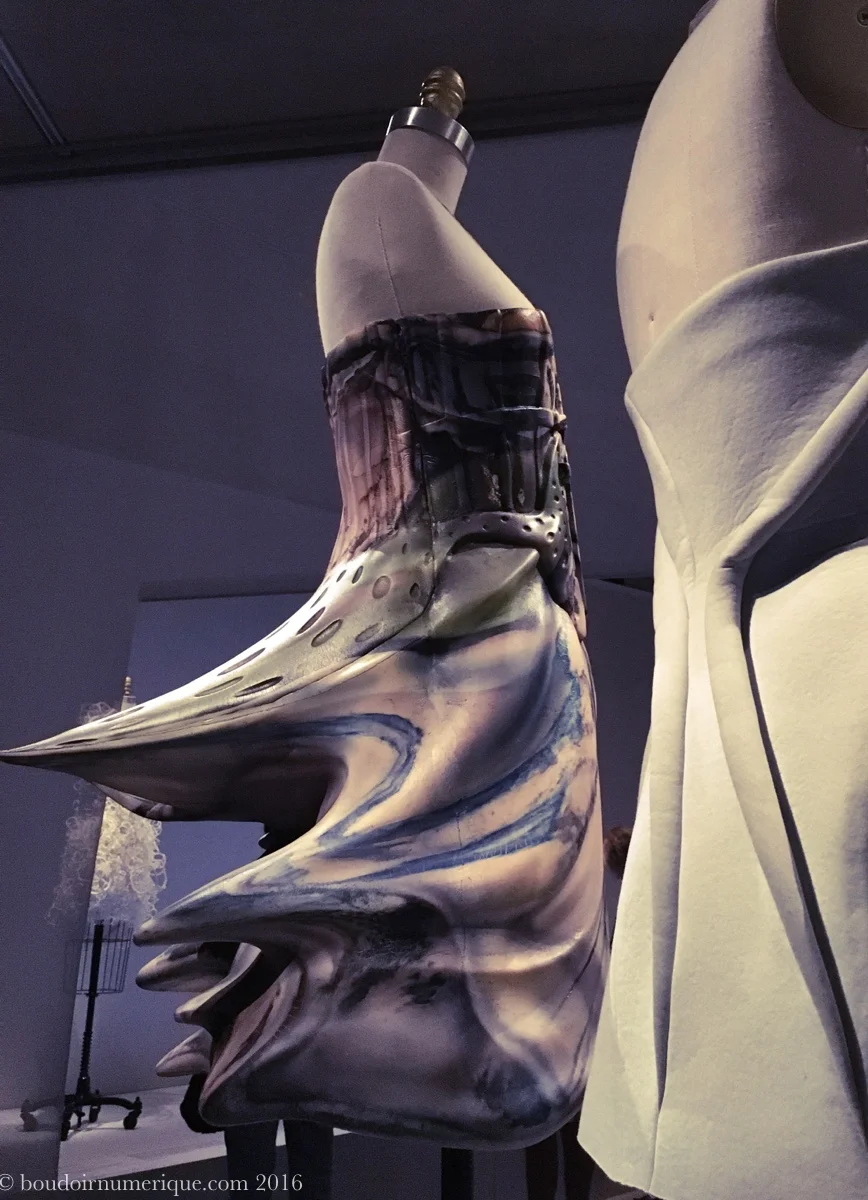 A l'arrière-plan, robe d'Hussein Chalayan, en mousse de polyurethane moulée et airbrushée (collection prêt-à-porter printemps/été 2009). Photo : Boudoir numérique. 