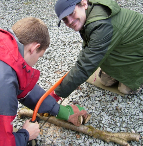Health & Safety - James and I sawing wood the forest school way. Note hands through and above the blade to keep the wood stable and making it difficult to cut yourself if the blade jumps. Bare hands on the handle to get a good grip.