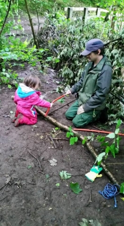 Children learn safety rules and to assess risks. Here a child is learning to use a tool safely to help make a hazel hurdle.