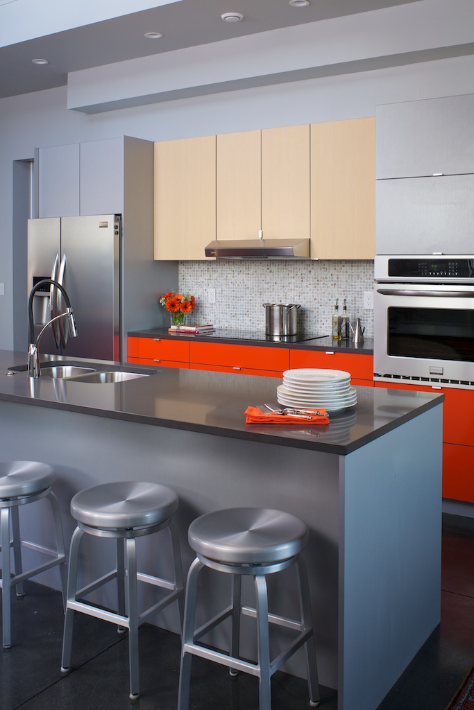 Why do one color when you can do three? Thanks to kabi's extensive line of finishes mixing is always an option. Here the center island is sheathed in the same material as the upper cabinets. The calmer colors allow the bright orange to pop but not overwhelm the space.