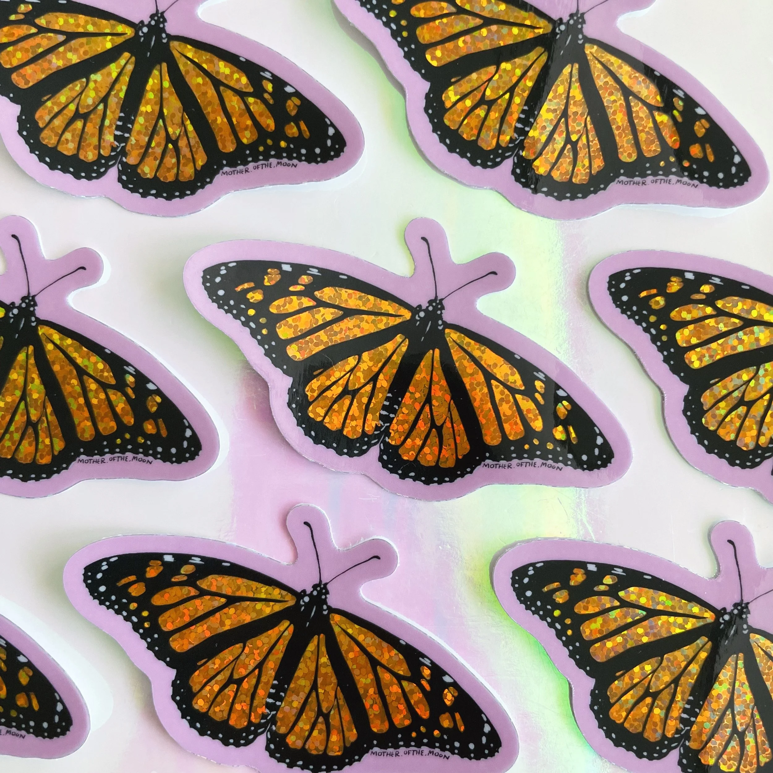 holographic glitter vinyl sticker of my monarch butterfly illustration against a pink background
