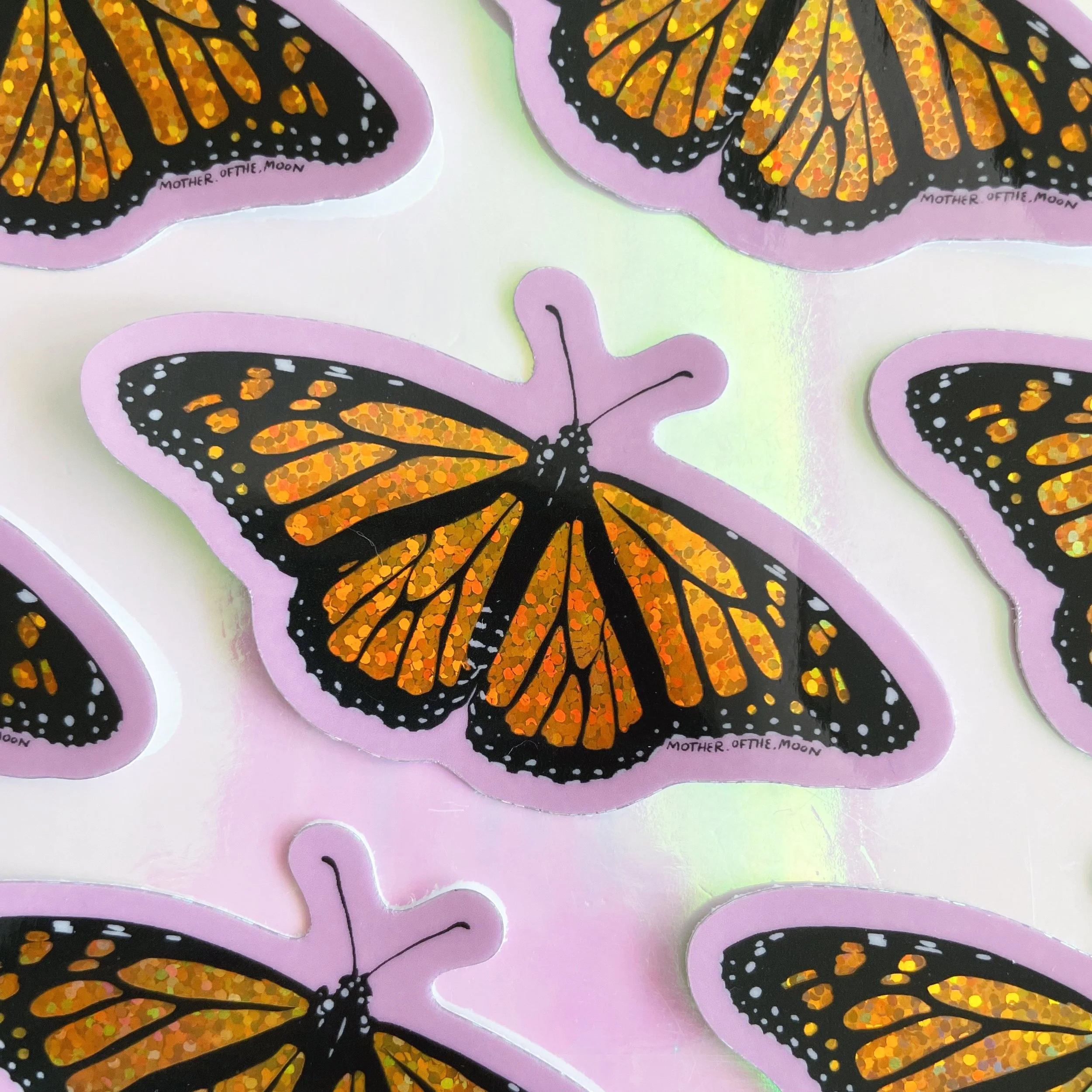 holographic glitter vinyl sticker of my monarch butterfly illustration against a pink background