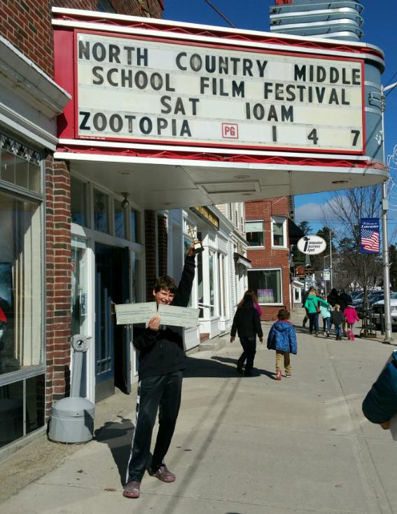 Cole proudly holds up a trophy and two giant checks for Woodland!