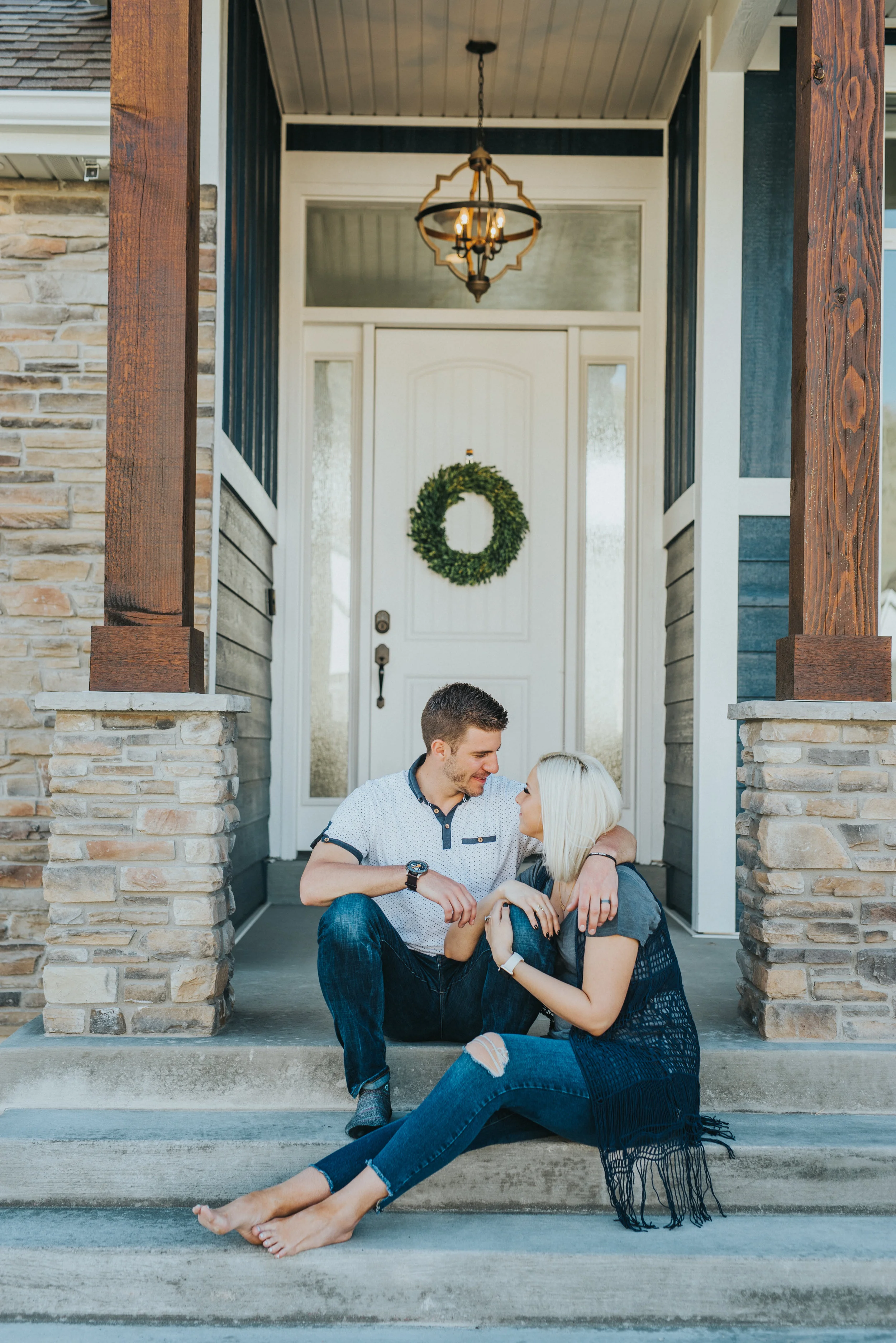  couple lifestyle photoshoot in home photo session cache valley photographer front porch pictures couple sitting on steps front door decor inspo casual photoshoot casual outfits blue jeans couple looking at each other couple posing ideas what to wear