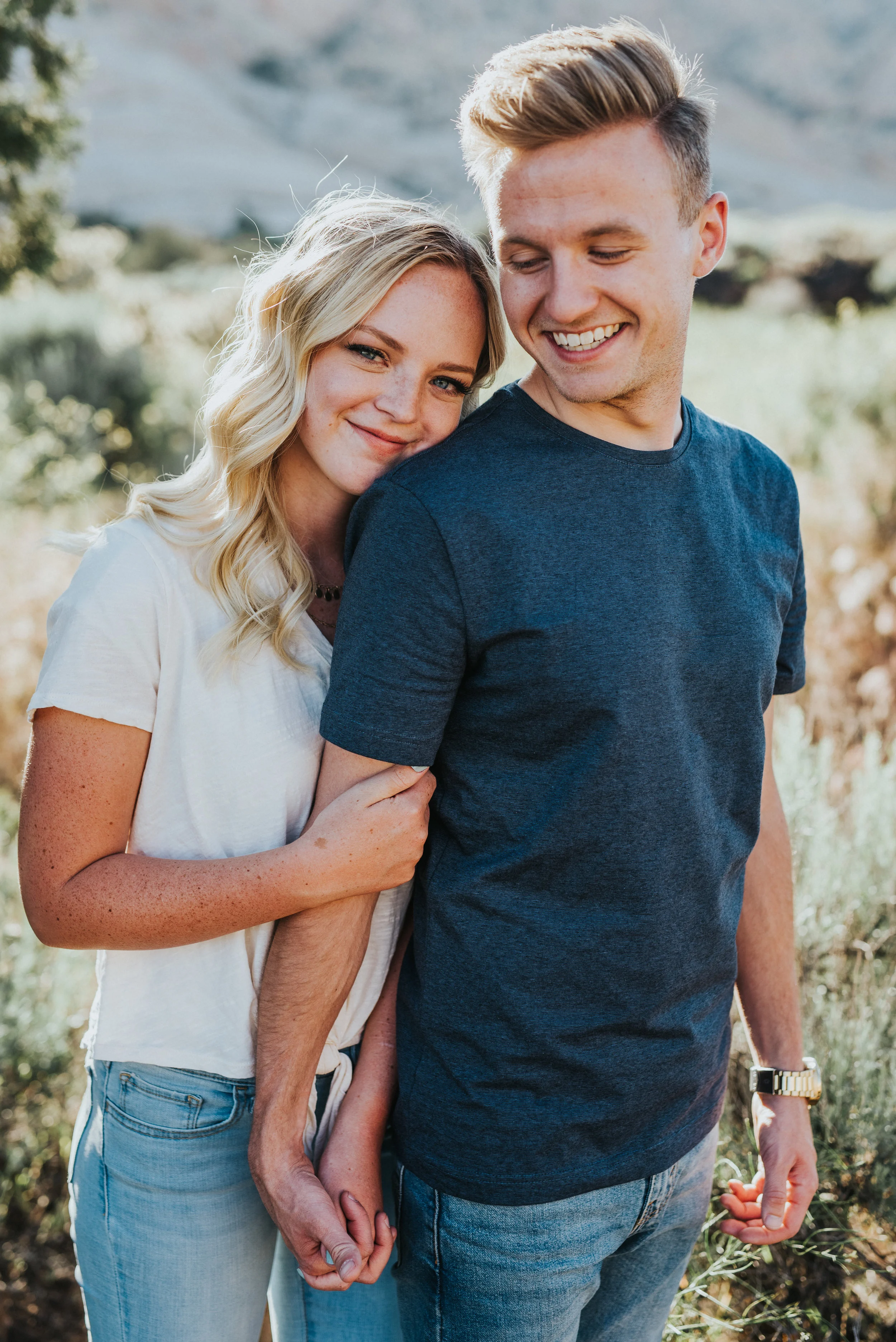  hugging head on shoulder playful natural engagement session tall grass background snow canyon utah saint george utah northern utah photographer professional navy shirt jeans outdoorsy #saintgeorgephotography #snowcanyon #engagementsession #utah #hai