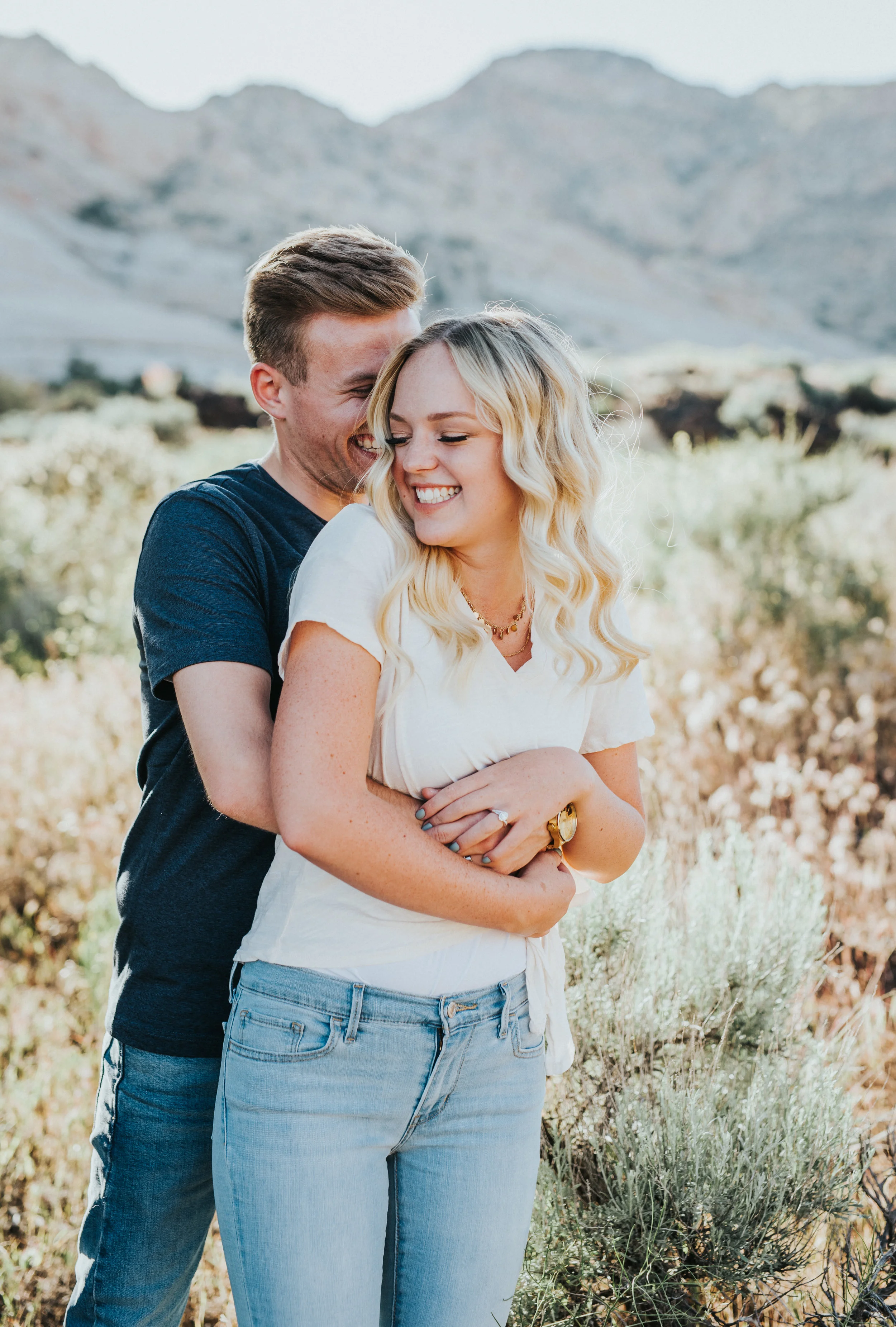  whispering sweet nothings happy hugging holding natural engagement session saint george utah dessert snow canyon utah casual photos jeans tshirt dirt pathway tall grass nothern utah photography #saintgeorgephotography #snowcanyon #engagementsession 