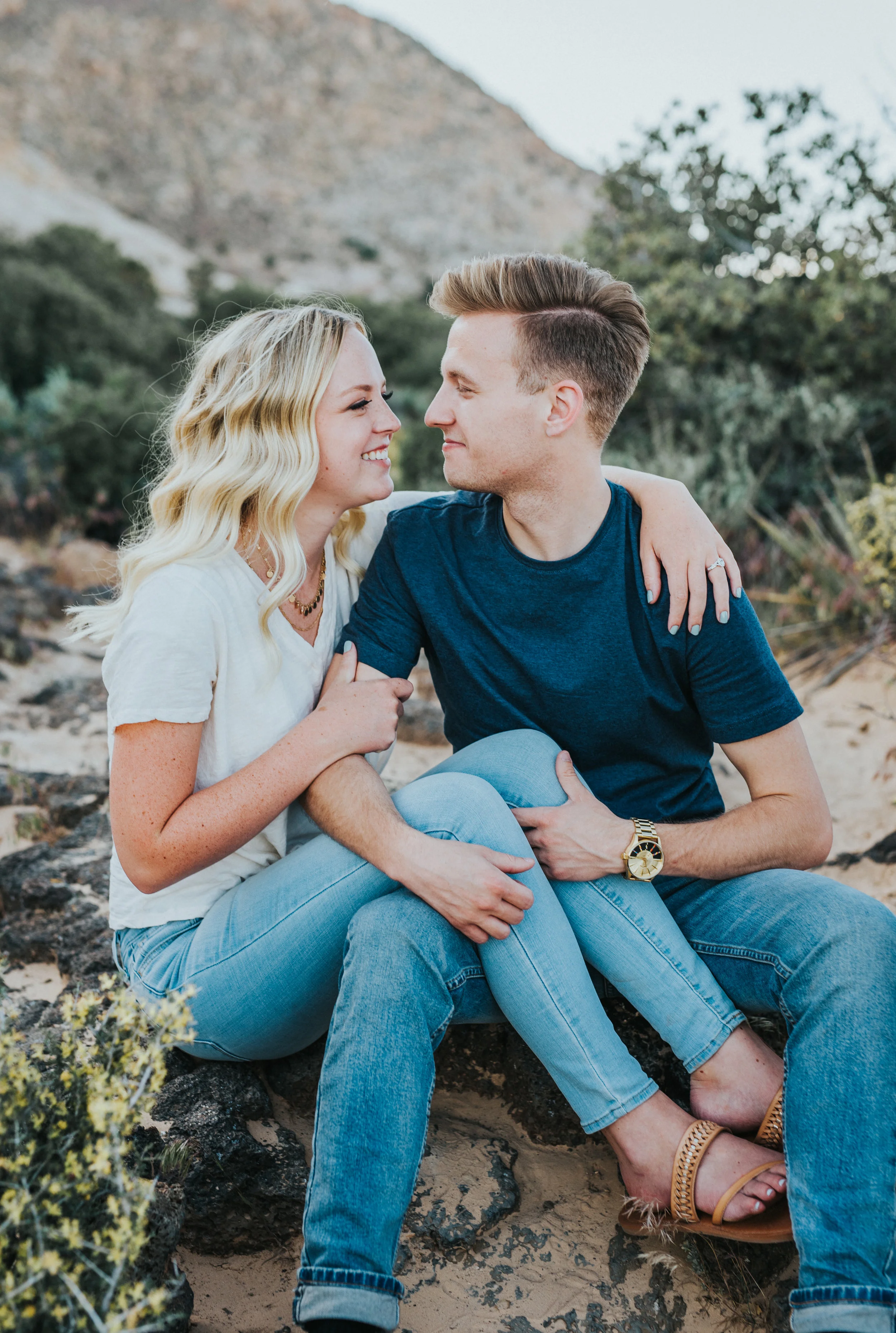  blonde hair inspiration wavy hair casual engagement session tshirt jeans sitting hugging cuddling playful desert landscape mountains dirt path northern utah professional photography #saintgeorgephotography #snowcanyon #engagementsession #utah #hairi
