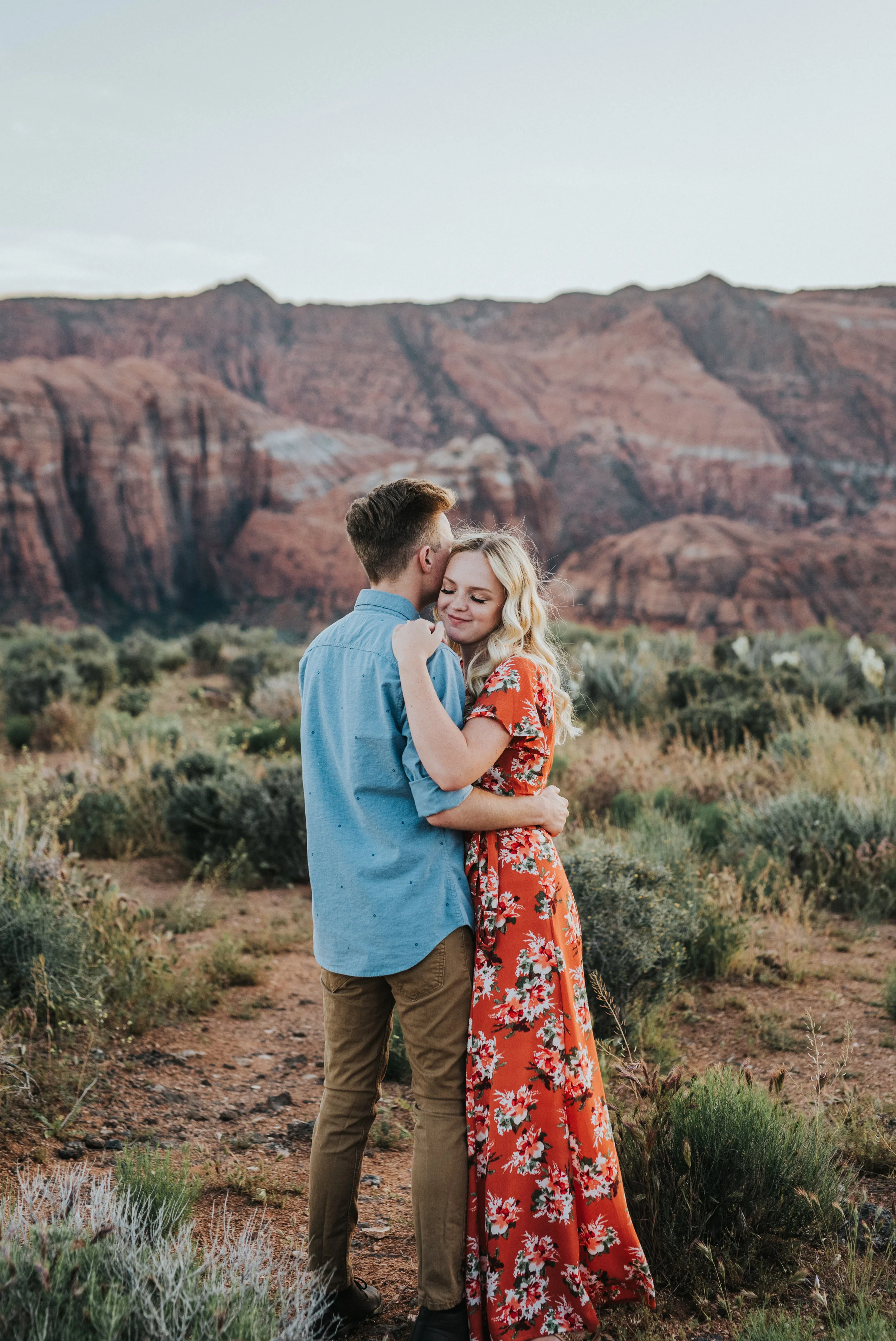  red rocks mountain background saint george utah engagement session photography burnt orange floral modest long dress dirt pathway desert romantic sunset northern utah photography #saintgeorgephotography #snowcanyon #engagementsession #utah #hairinsp
