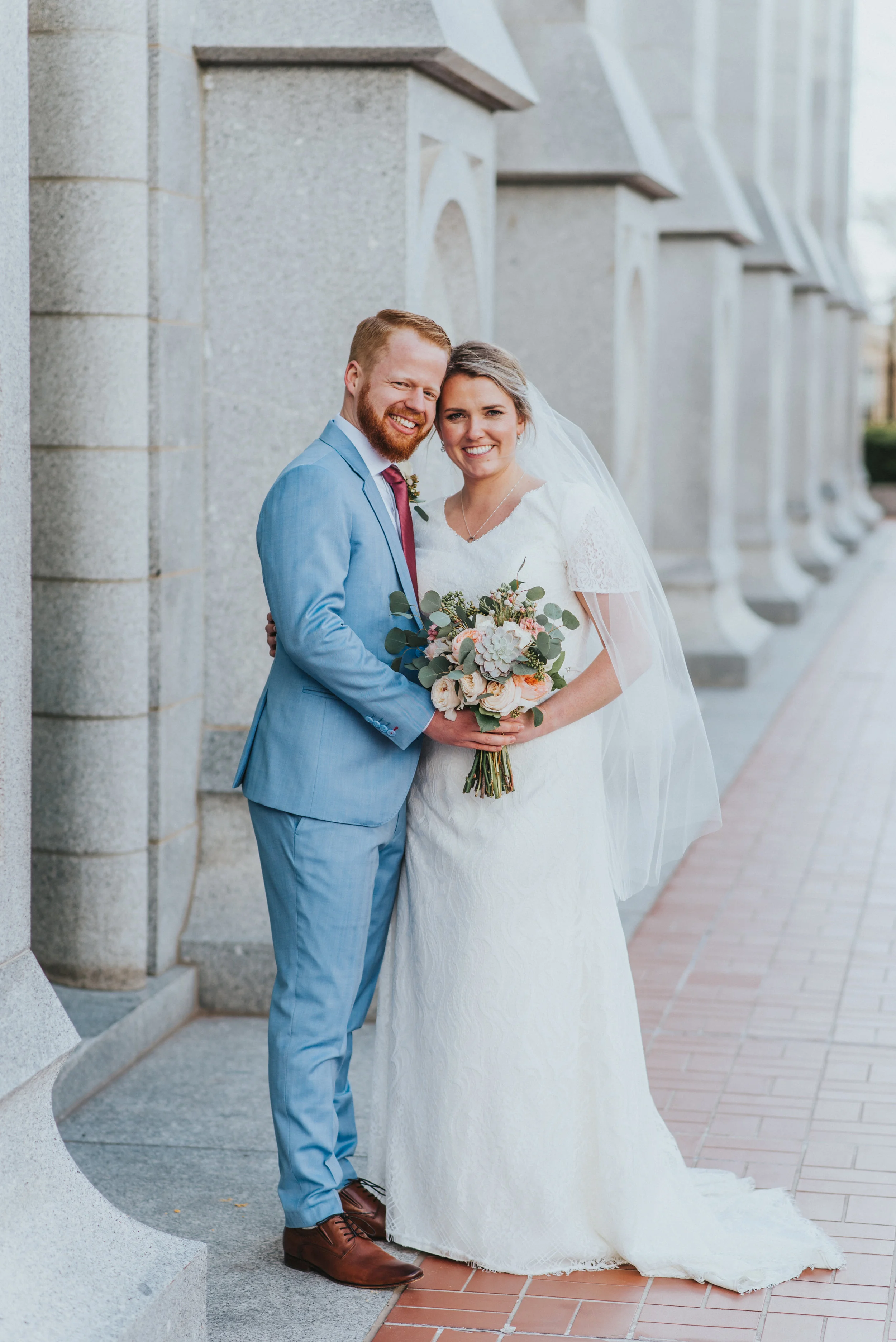  salt lake city temple columns wedding couple photos hugging smiling professional northern utah photography salt lds modest lace wedding dress long wedding veil light blue suit groom bride photos #northernutahweddingphotographer #saltlakecityphotogra