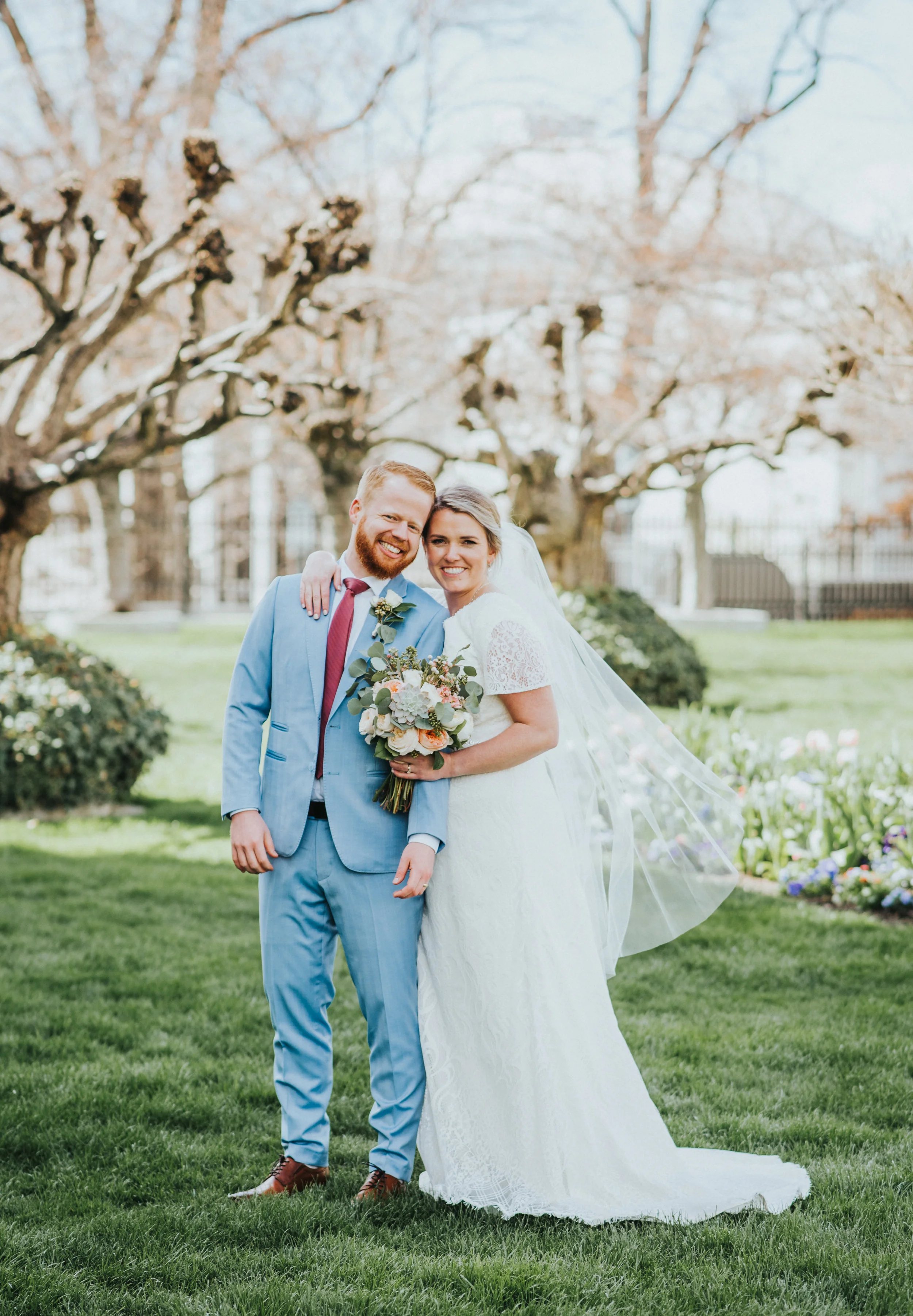  winter temple wedding lds salt lake city utah norther utah photography professional billowing veil wedding photos pastel wedding colors red tie blue powdered suit temple grounds hugging smiling #northernutahweddingphotographer #saltlakecityphotograp