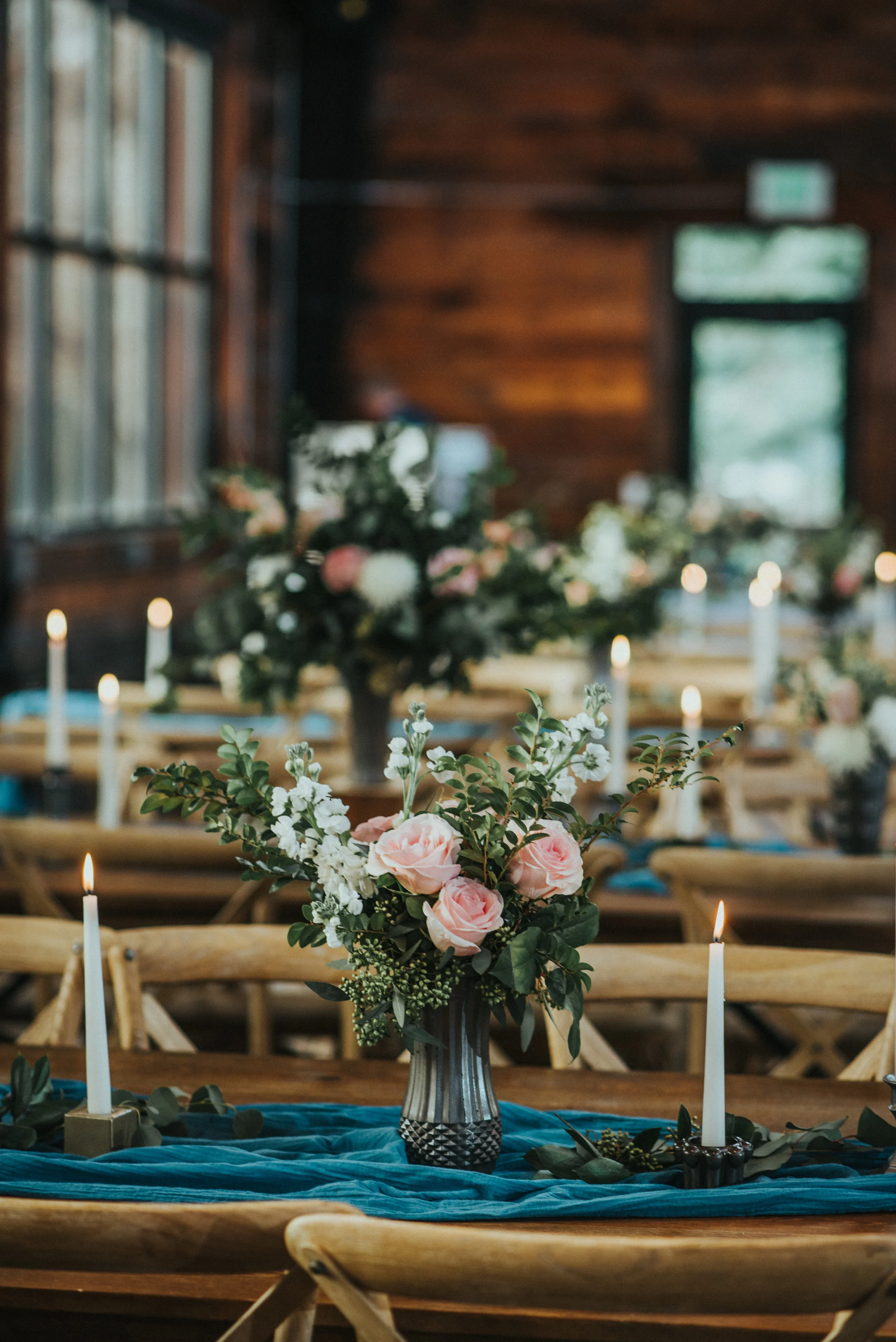  rows of candle lit tables pastel rose floral arrangement centerpieces rustic wedding decor wood cabin walls wood reception tables salt lake city utah northern utah professional wedding photographer #northernutahweddingphotographer #saltlakecityphoto