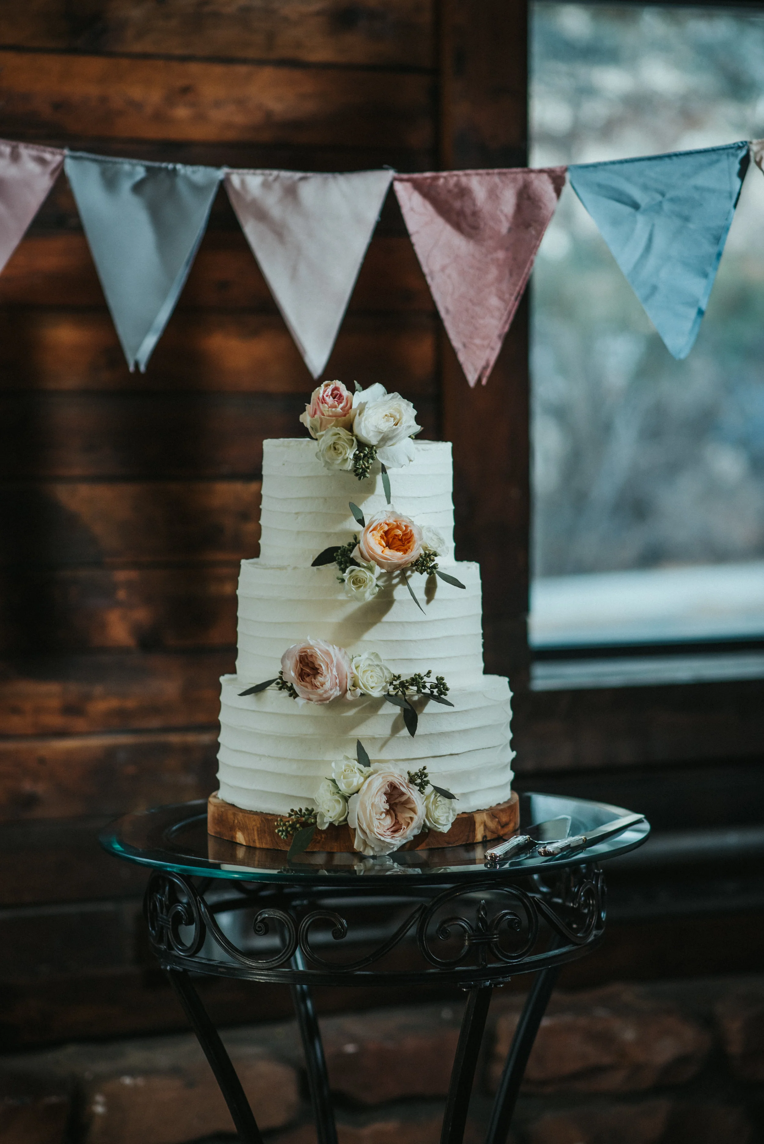  white three tiered wedding cake minimal wedding cake pastel roses on cake rustic wedding decor pastel wedding color scheme cake cutting knot and pine alpine barn wedding reception northern utah wedding photography salt lake city utah #northernutahwe