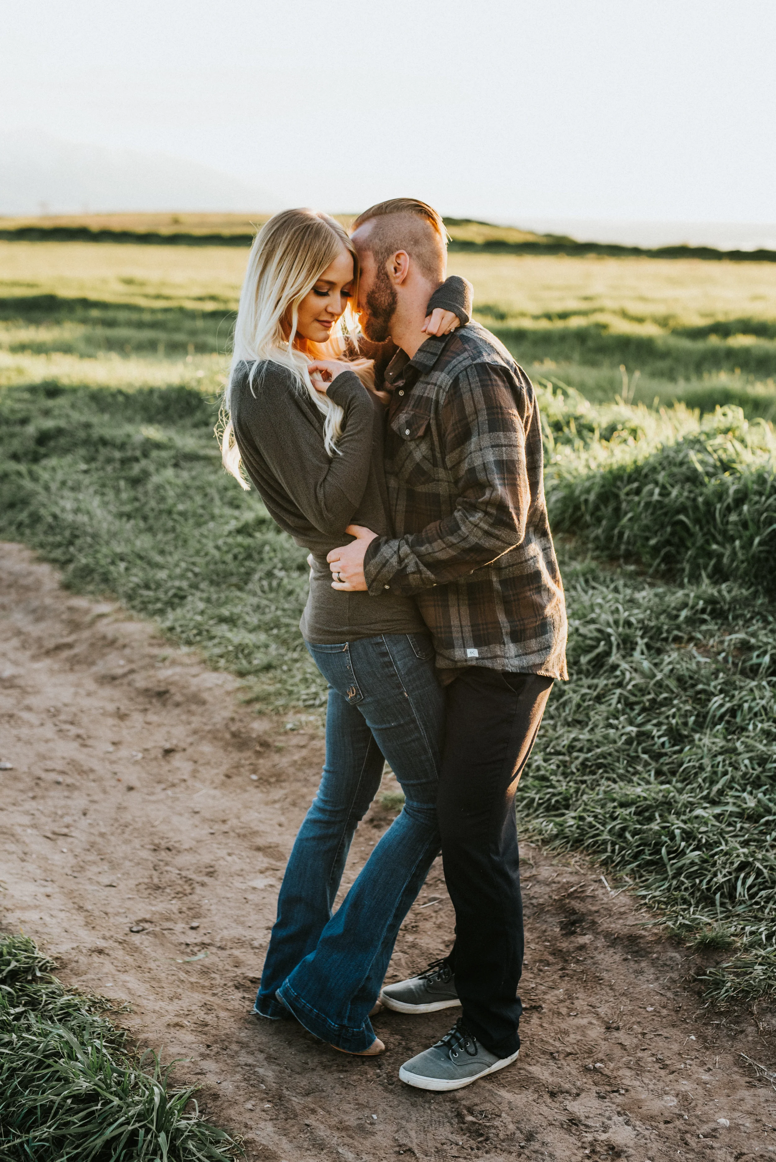  hugging kissing standing greenery background fields dirt pathway nature tunnel springs engagement northern utah photography cache valley professional photographer fall colored outfit inspiration plaid shirt romantic intimate photos #engagementphotog