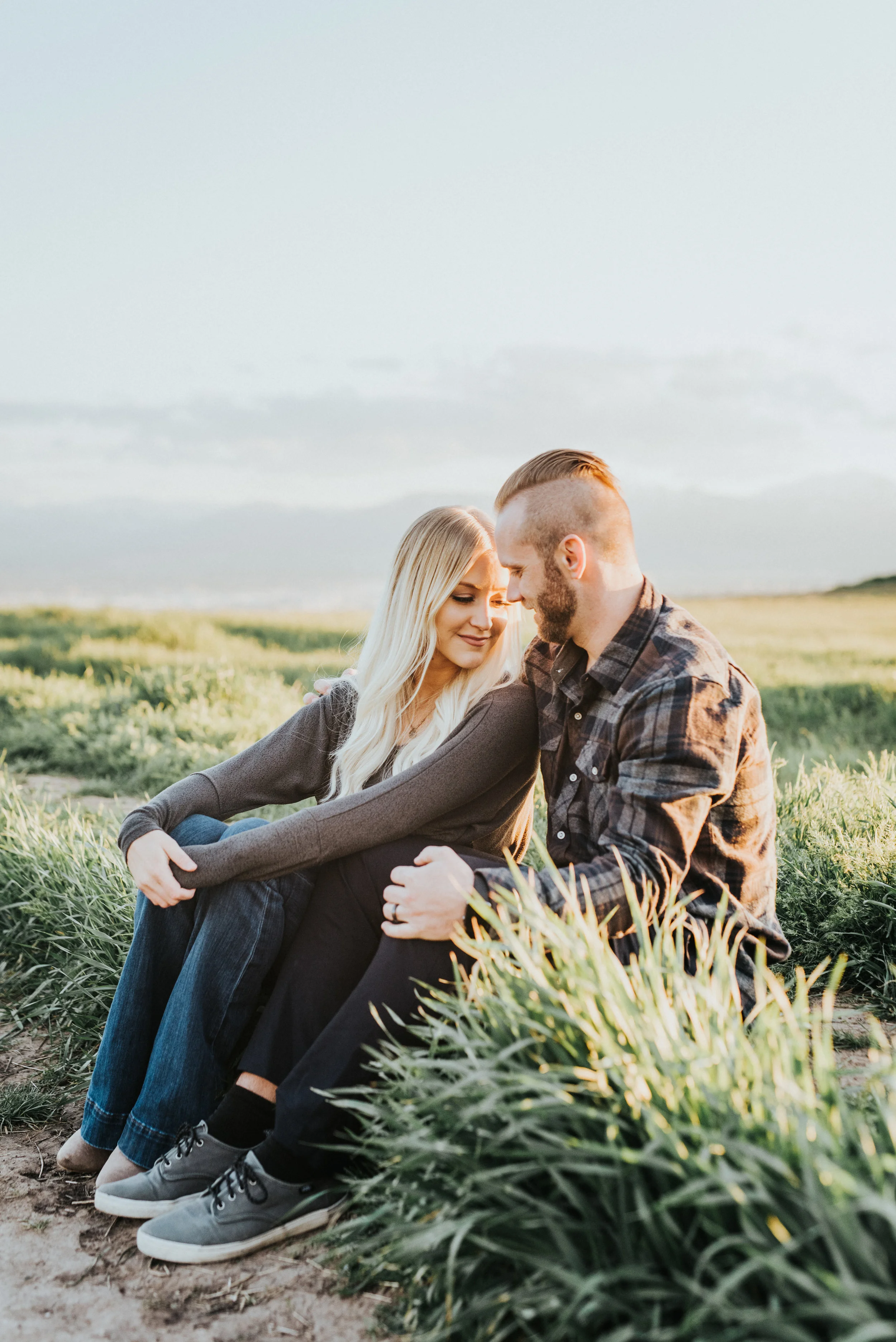  cache valley utah professional photographer engagement session sitting green field blue sky fall family photos sitting holding hands hugging blonde hair inspiration logan utah utah mountains plaid shirt fall colored color scheme #engagementphotograp