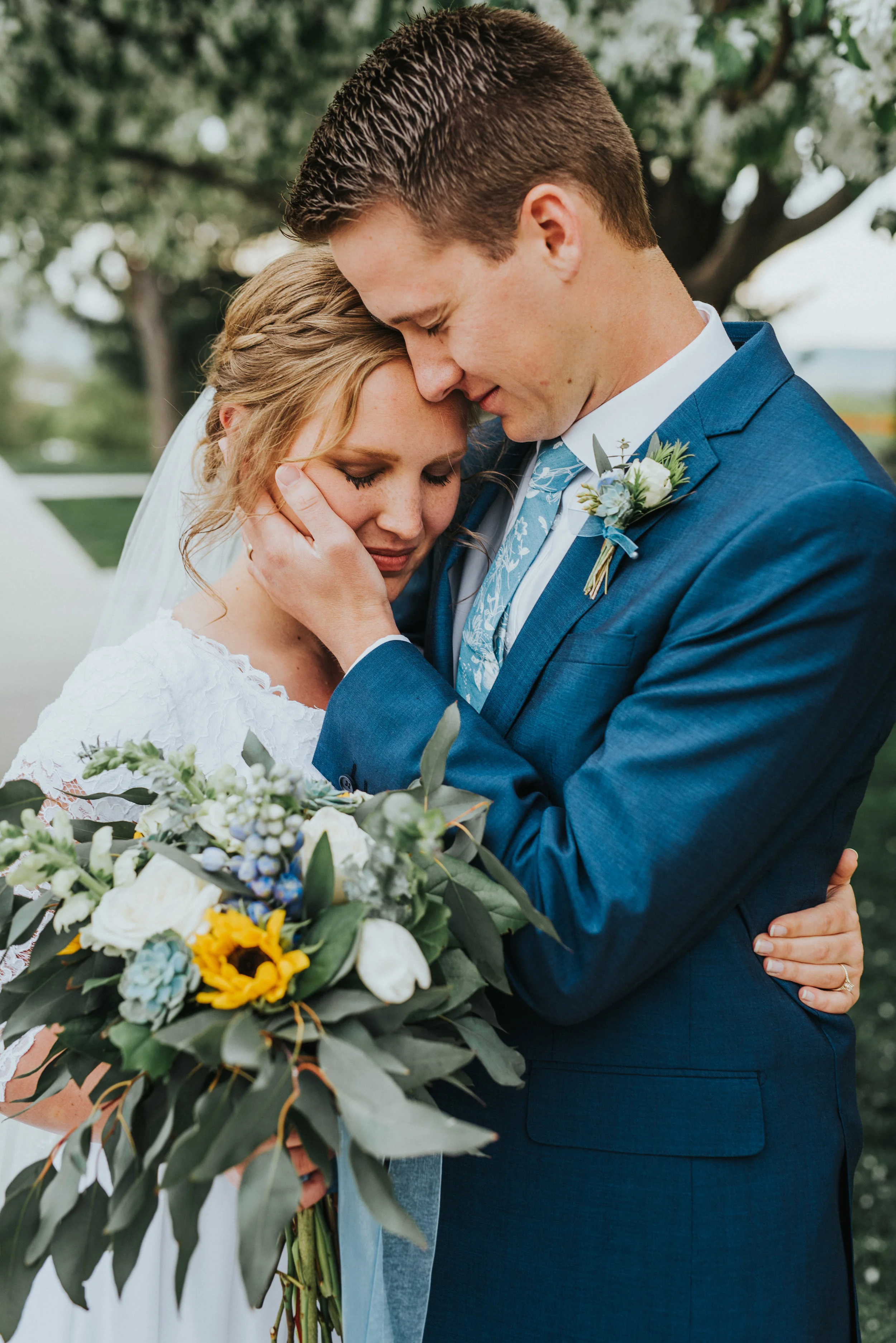  neutral wedding makeup messy braided wedding updo cuddling hugging touching cheek bride and groom lace wedding dress blue wedding suit sunflower wedding bouquet best cache valley photographer wedding formals #Loganutah #cachevalleyphotographer #Ido 
