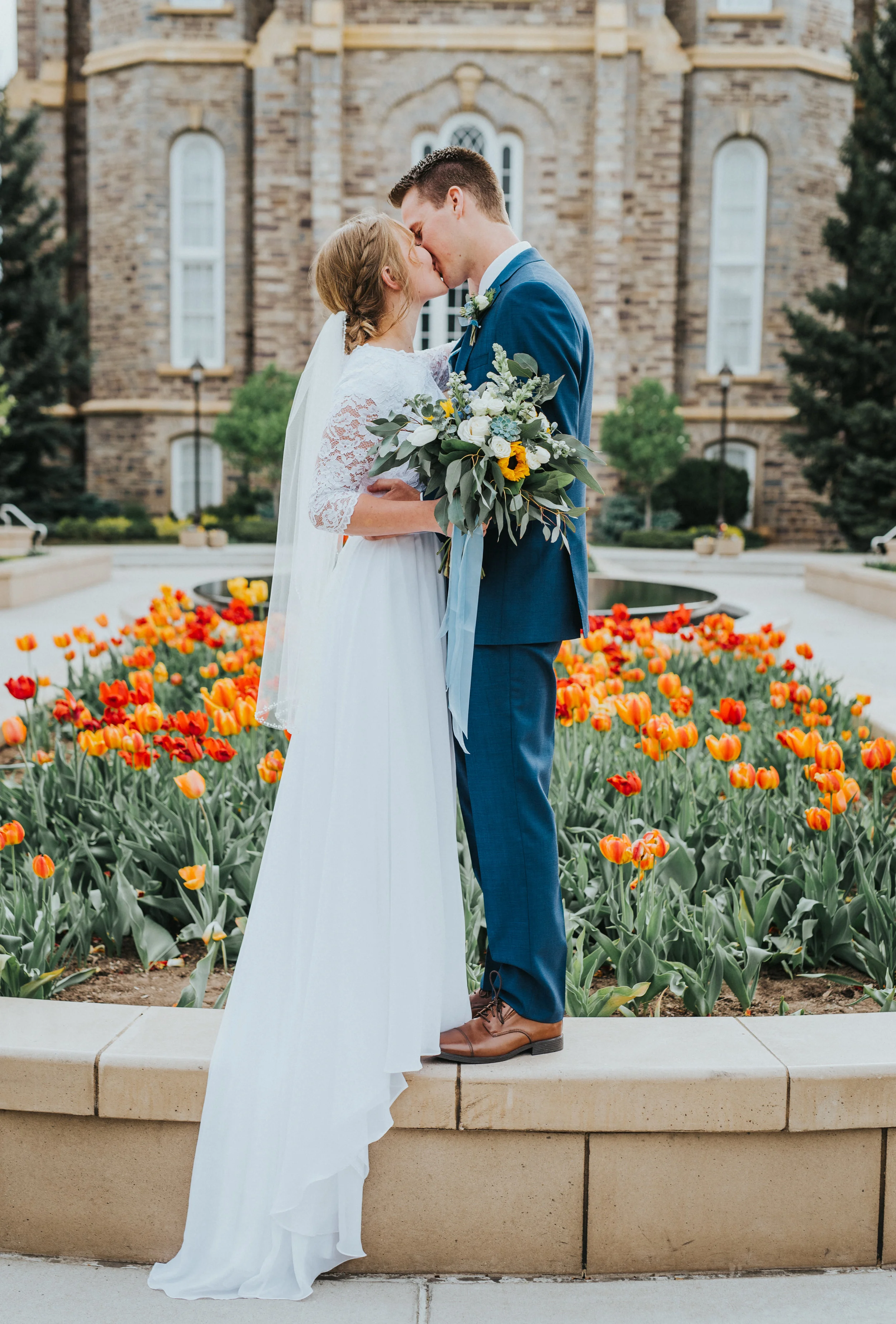  lds logan utah temple wedding spring wedding red and orange tulips kissing hugging just married romantic wedding poses draped wedding train best logan utah wedding photographer modest wedding dress #Loganutah #cachevalleyphotographer #Ido #Isaidyes 