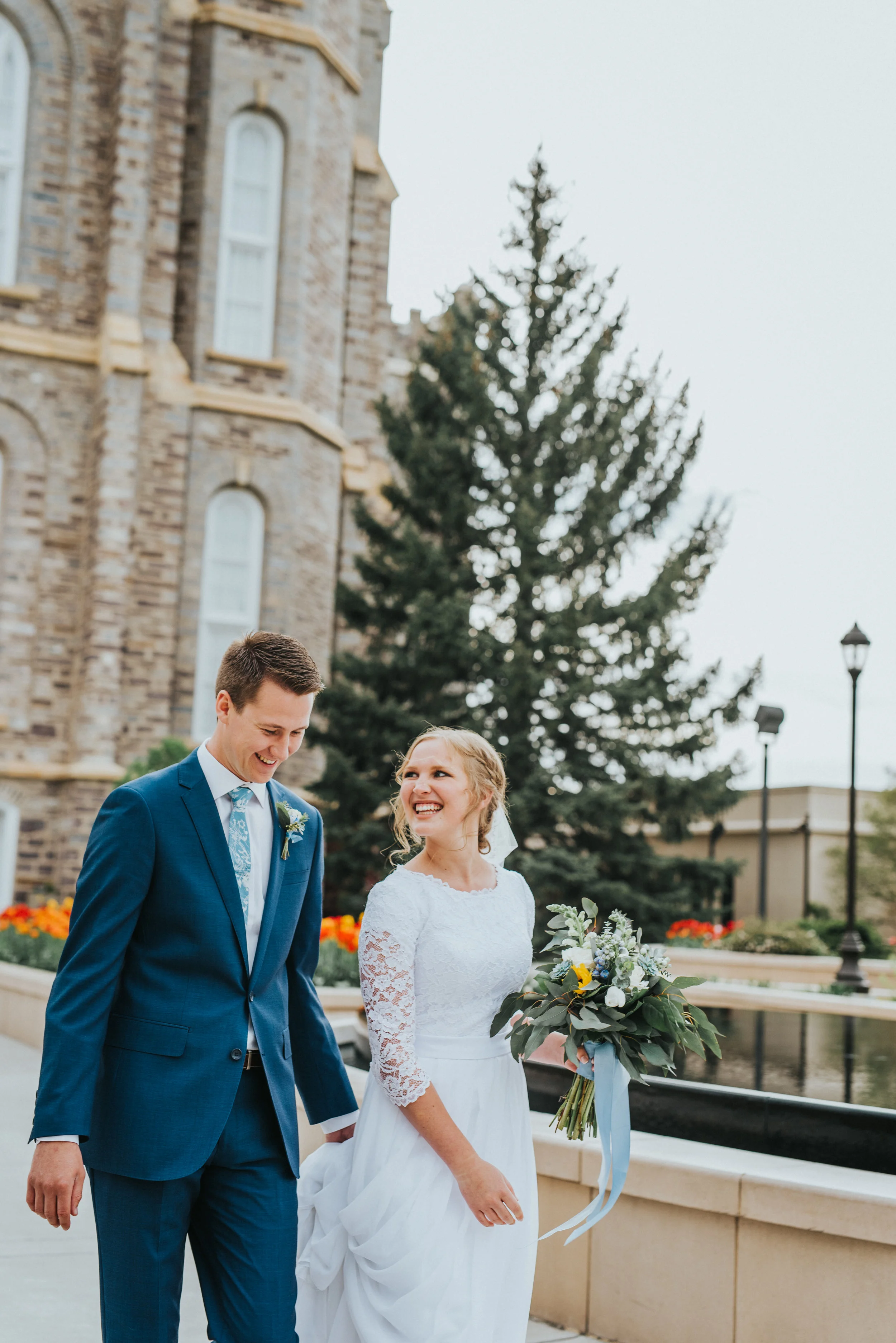  candid photography holding hands happy in love wedding photos groom holding wedding train baby blue bouquet ribbon three quarter sleeved lace wedding dress modest lds logan utah temple happy in love cache valley photographer #Loganutah #cachevalleyp
