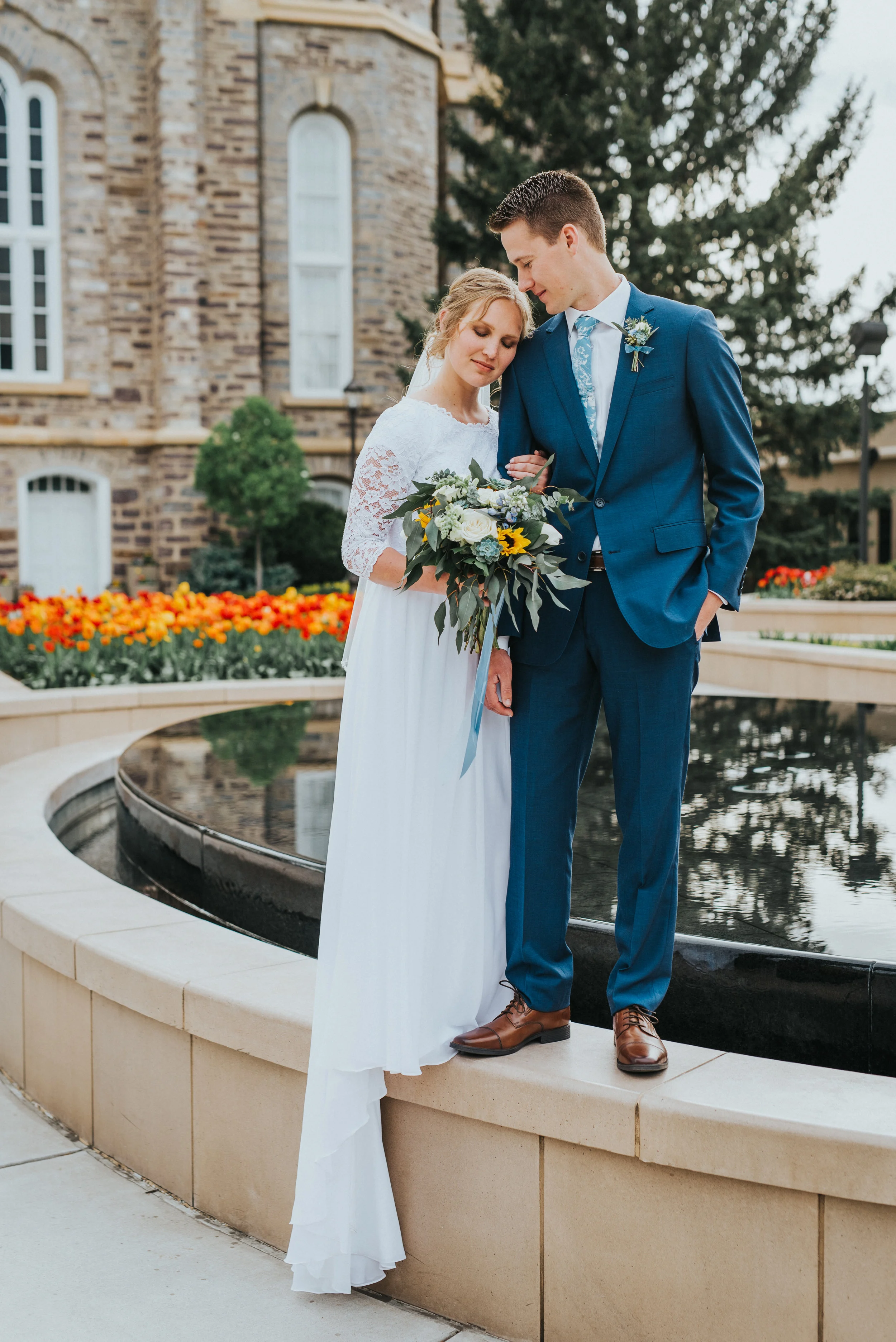  spring wedding orange and red tulips cache valley professional wedding photographer logan utah lds temple grounds water fountain kissing head messy braided wedding updo draped wedding dress train blue wedding suit and tie cache valley wedding photog