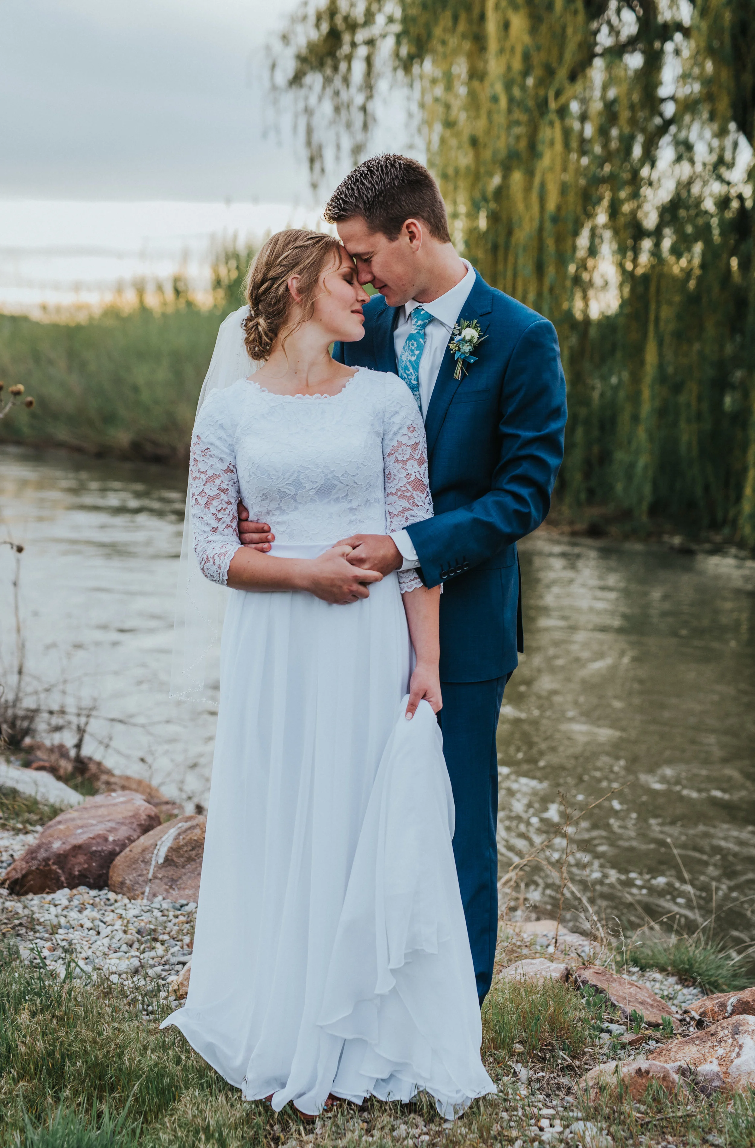  empire waist three quarter lace sleeved wedding dress modest holding wedding dress messy braided wedding updo hair inspiration navy wedding suit stream willow tree sunset cache valley wedding photography #Loganutah #cachevalleyphotographer #Ido #Isa