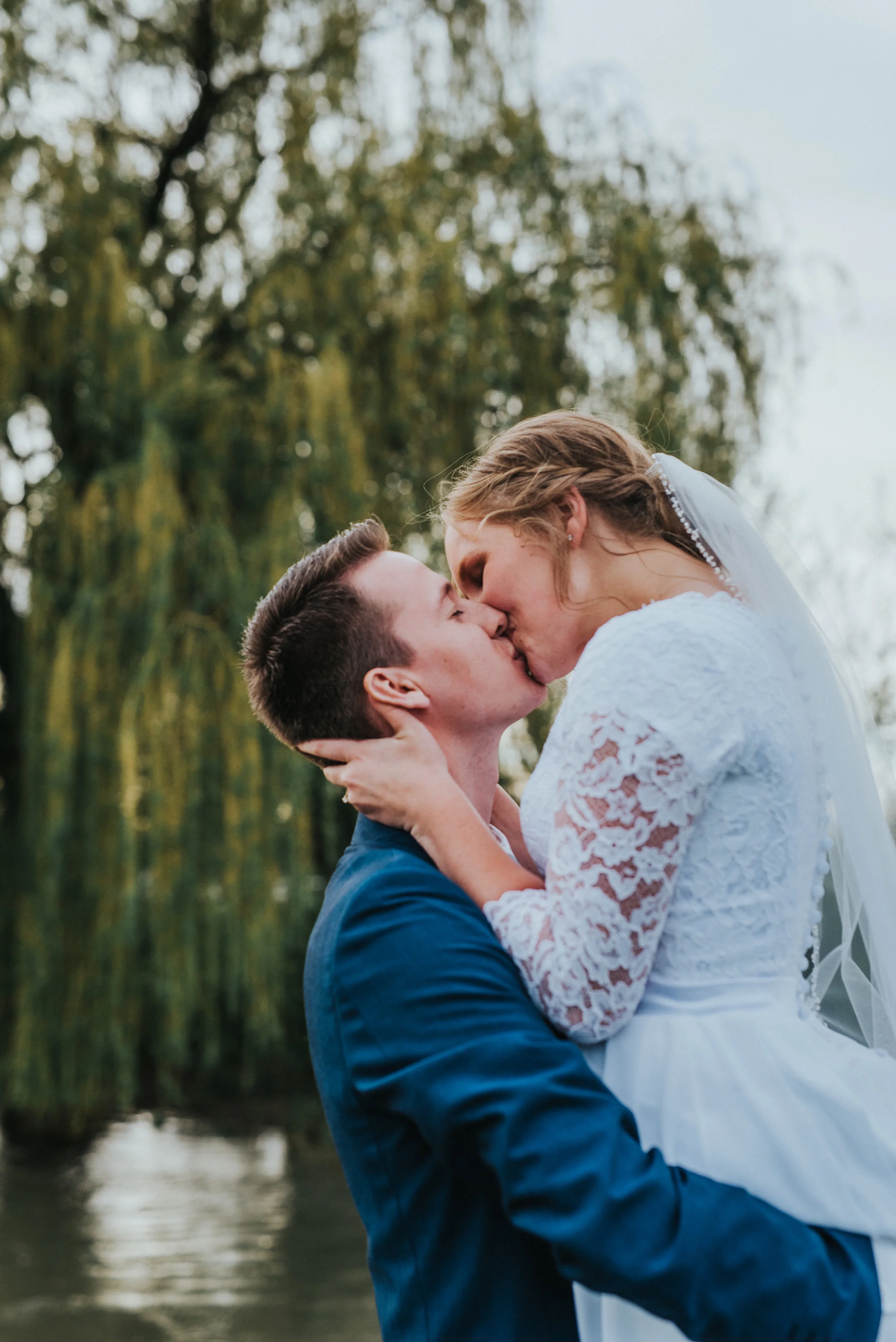  modest floral lace sleeved wedding dress holding hugging picking up bride kissing romantic passionate braided wedding updo wedding veil stream willow tree logan utah cache valley photographer #Loganutah #cachevalleyphotographer #Ido #Isaidyes #weddi