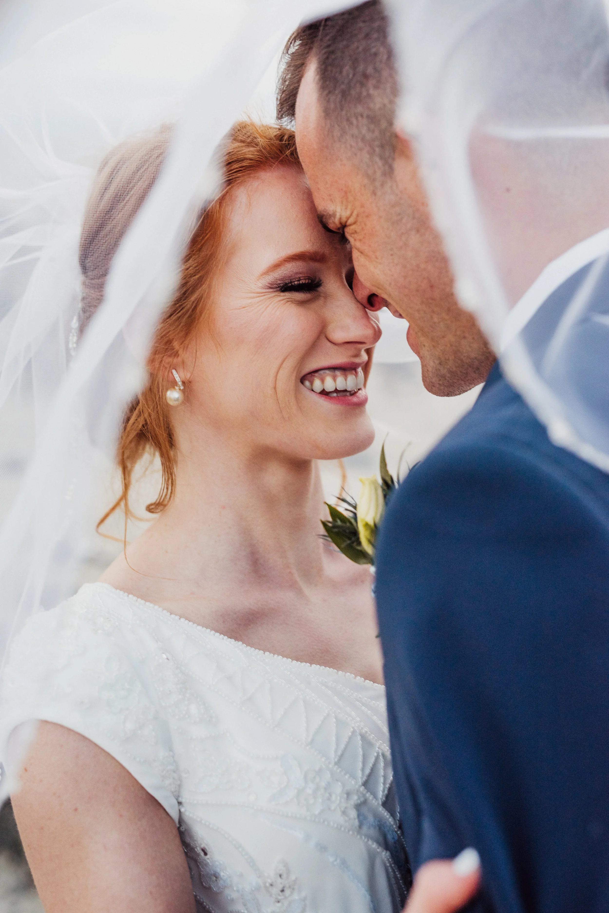  billowy lace wedding veil kissing under veil foreheads touching romantic navy wedding suit red hair wedding updo modest wedding dress salt lake city wedding photographer #spiraljetty #saltlakecityweddingphotographer #saltlake #ido #northernutahphoto