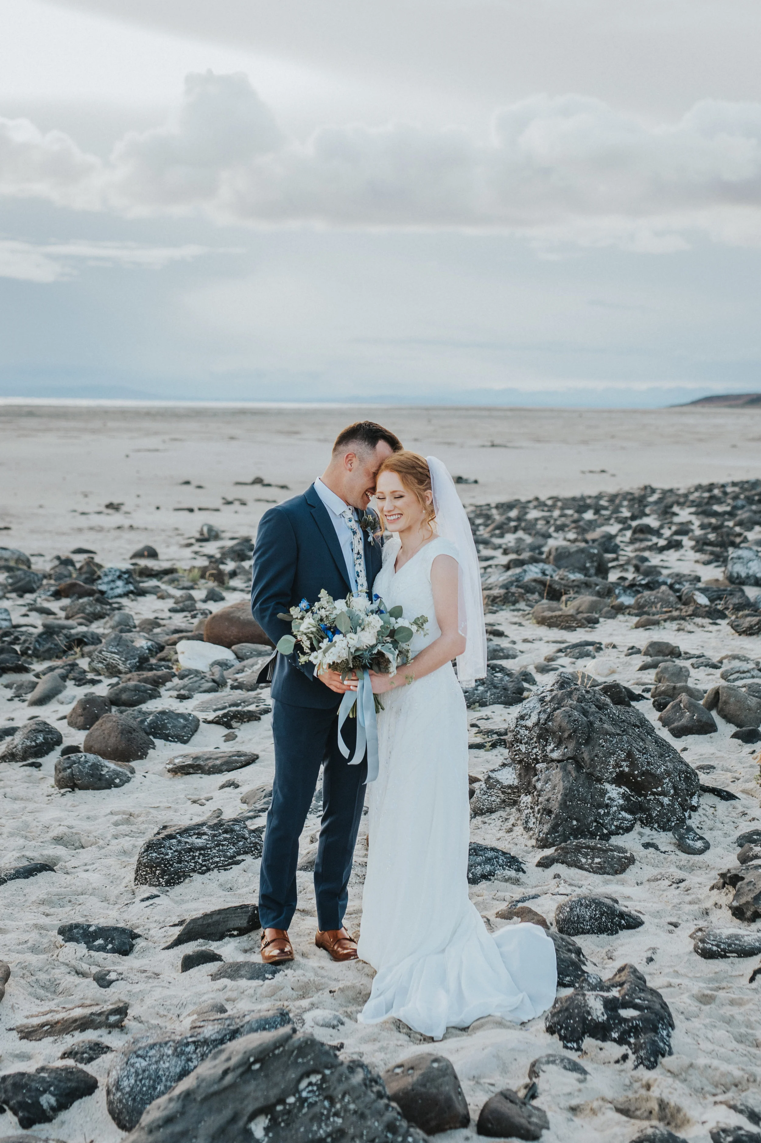  overcast bridal photoshoot sand rocks great salt lake hugging romantic whispering northern utah professional wedding photographer sunset #spiraljetty #saltlakecityweddingphotographer #saltlake #ido #northernutahphotographer #bridals #weddinginsp #ha
