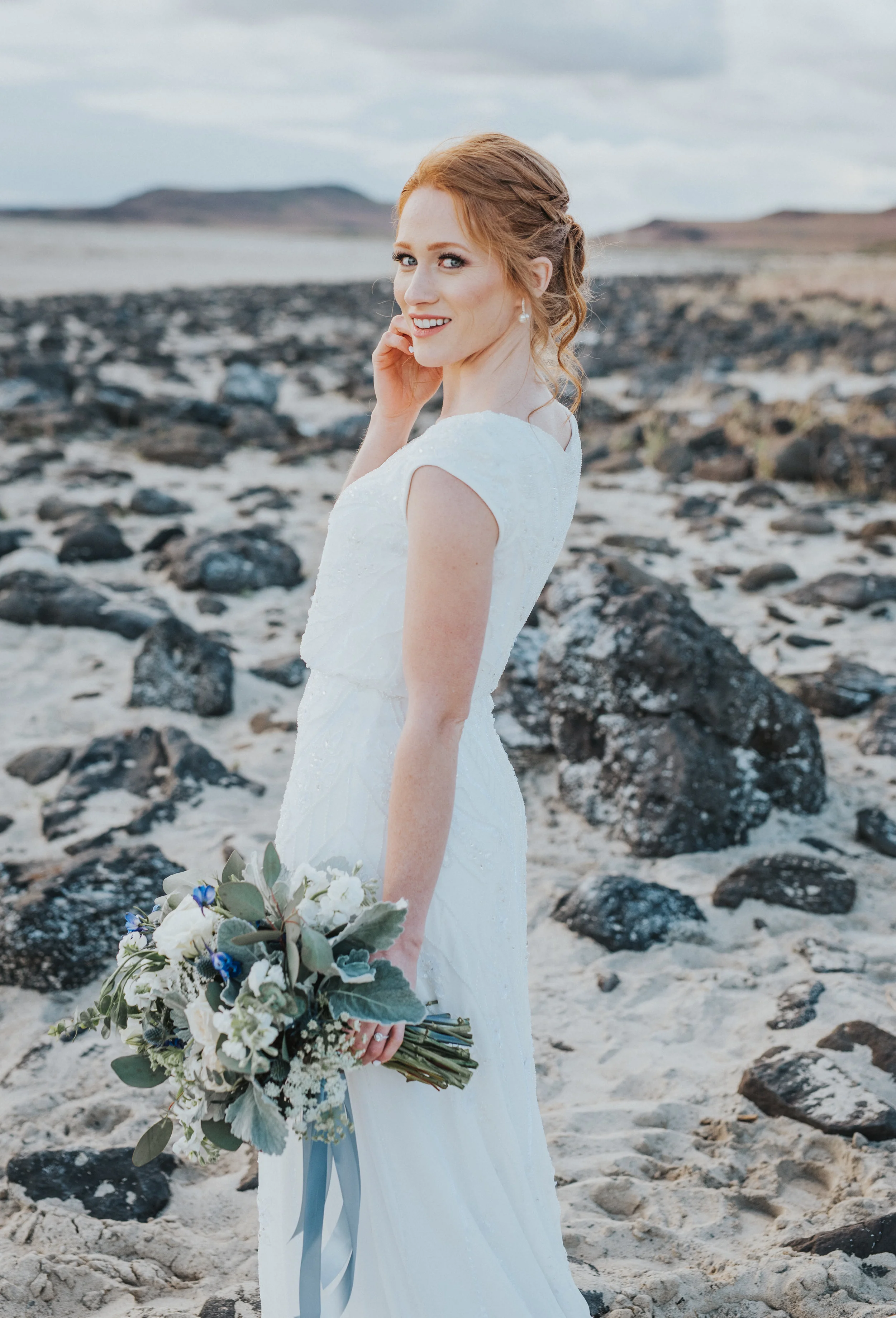  posed formal bridals bride sand rocks sunset first look cloudy sky red hair bridal updo professional wedding photographer salt lake city northern utah wedding photographer #spiraljetty #saltlakecityweddingphotographer #saltlake #ido #northernutahpho