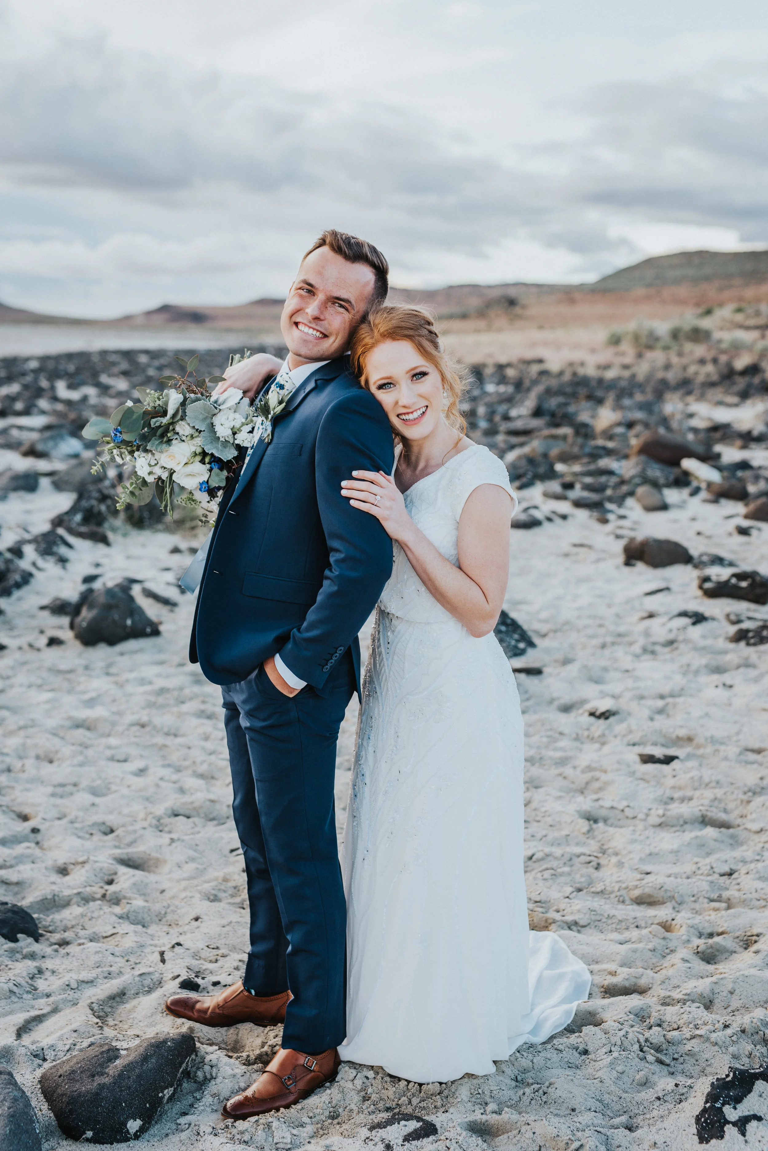  smiling formal bridal session hugging holding hands sand mountains the great salt lake bridal updo inspiration i do bride and groom #spiraljetty #saltlakecityweddingphotographer #saltlake #ido #northernutahphotographer #bridals #weddinginsp #hairins
