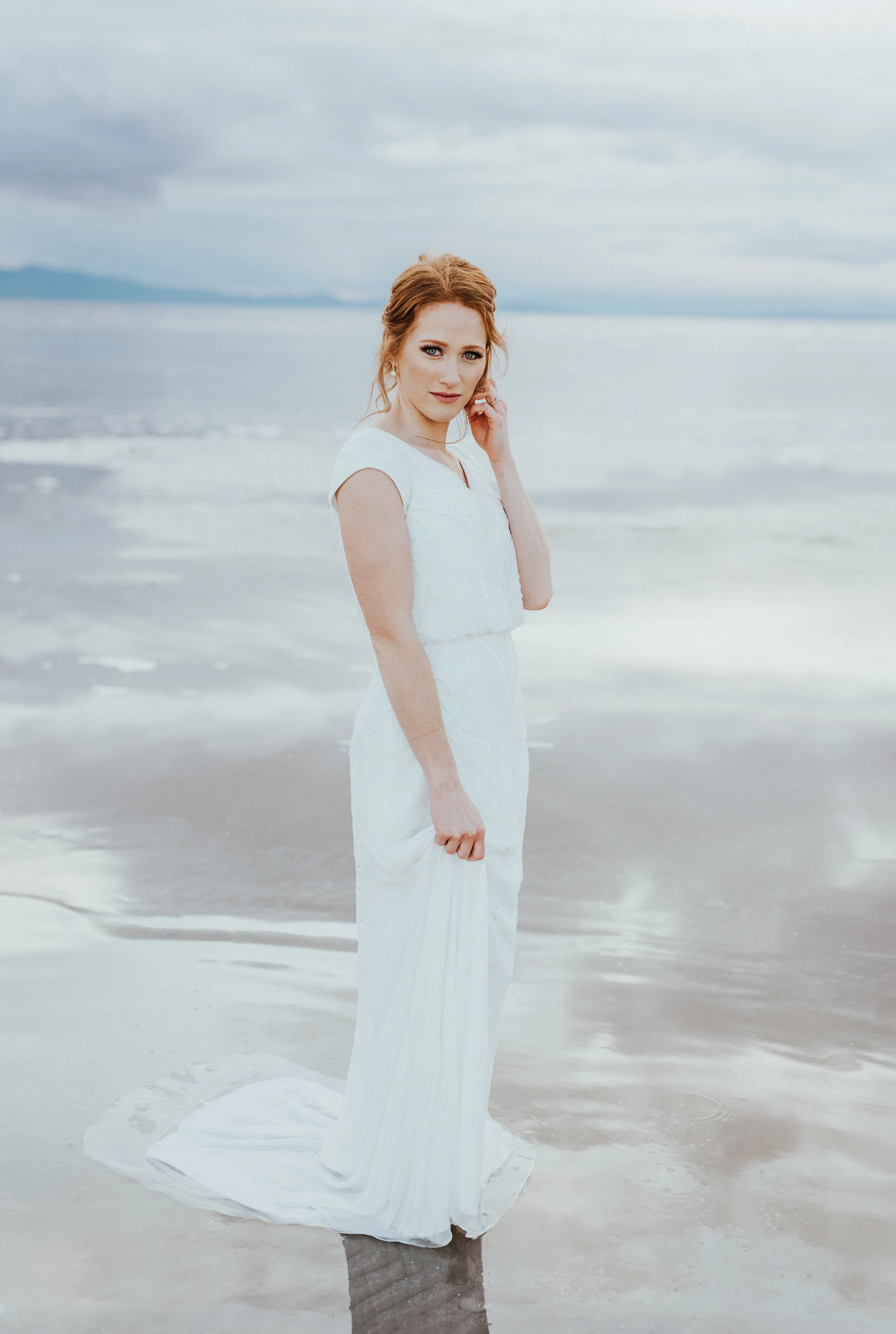  walking in water wedding dress cap sleeved wedding dress bridal updo red hair inspiration moody skies great salt lake sand water reflections northern utah wedding photographer #spiraljetty #saltlakecityweddingphotographer #saltlake #ido #northernuta