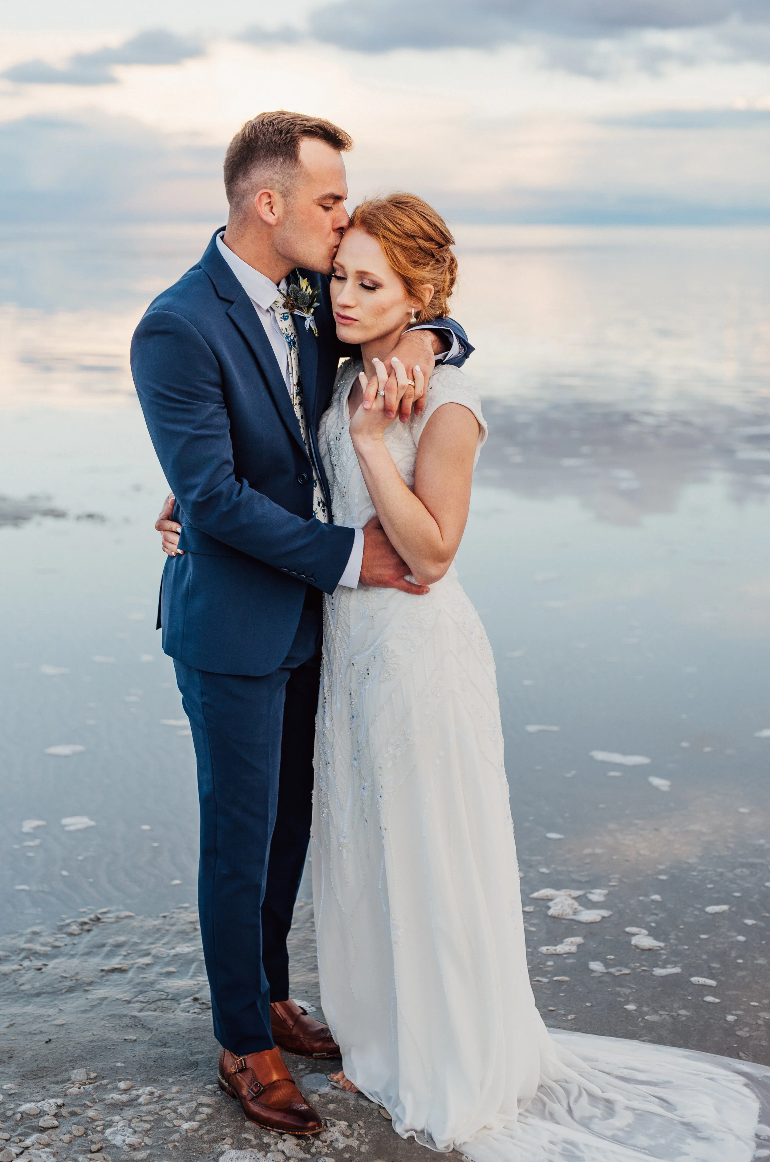  wedding portraits bridals hugging holding romantic kissing forehead red hair bridal updo modest white wedding dress navy groom suit north salt lake northern utah wedding photography professional #spiraljetty #saltlakecityweddingphotographer #saltlak