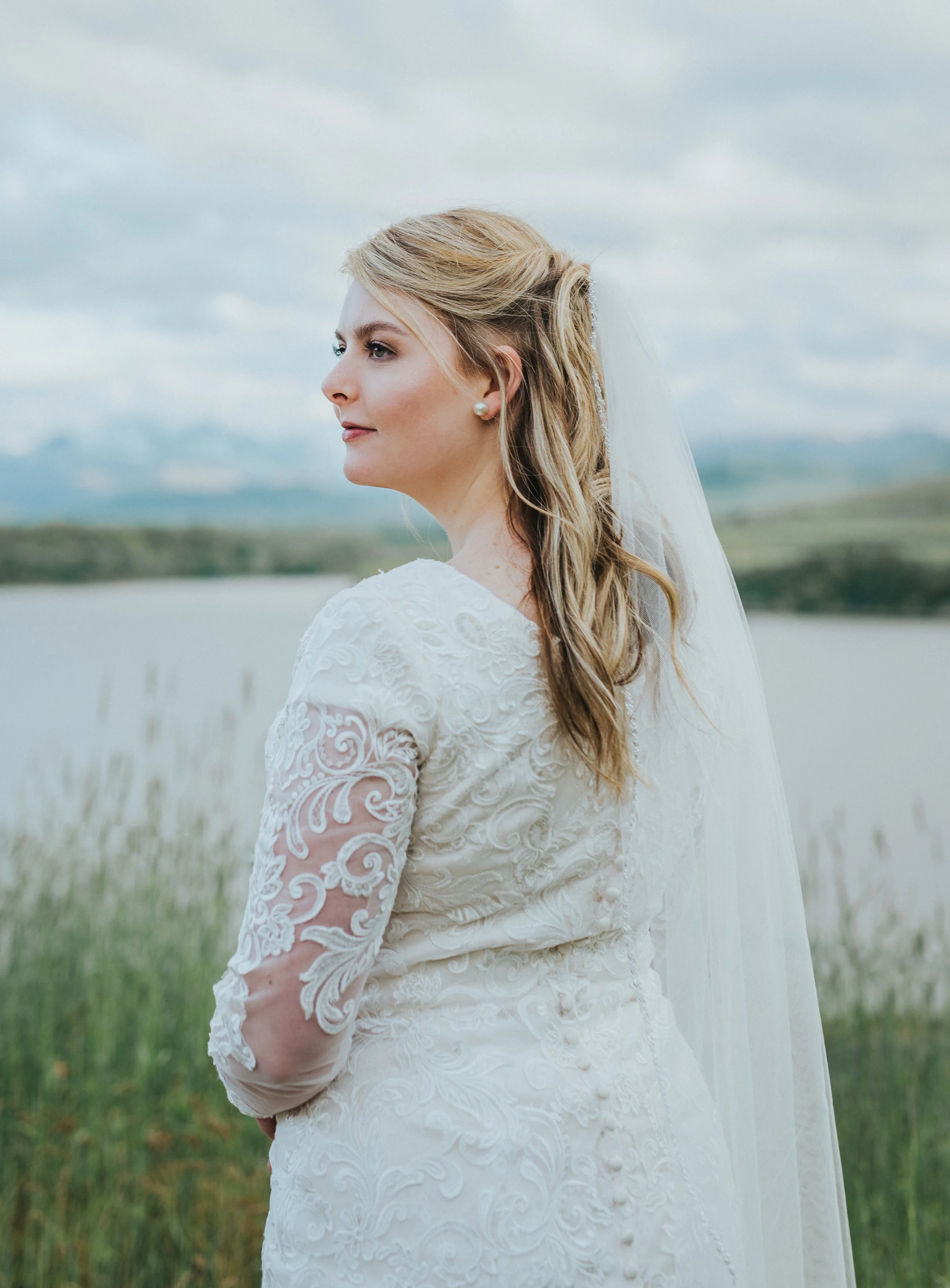  logan utah bridal photographer bride vintage wedding lave modest wedding dress mountain backdrop water long veil pearl earings timeless wedding black smith fork canyon hyrum utah northern utah photography #cachevalleyutah #hyrumutah #northernutahpho